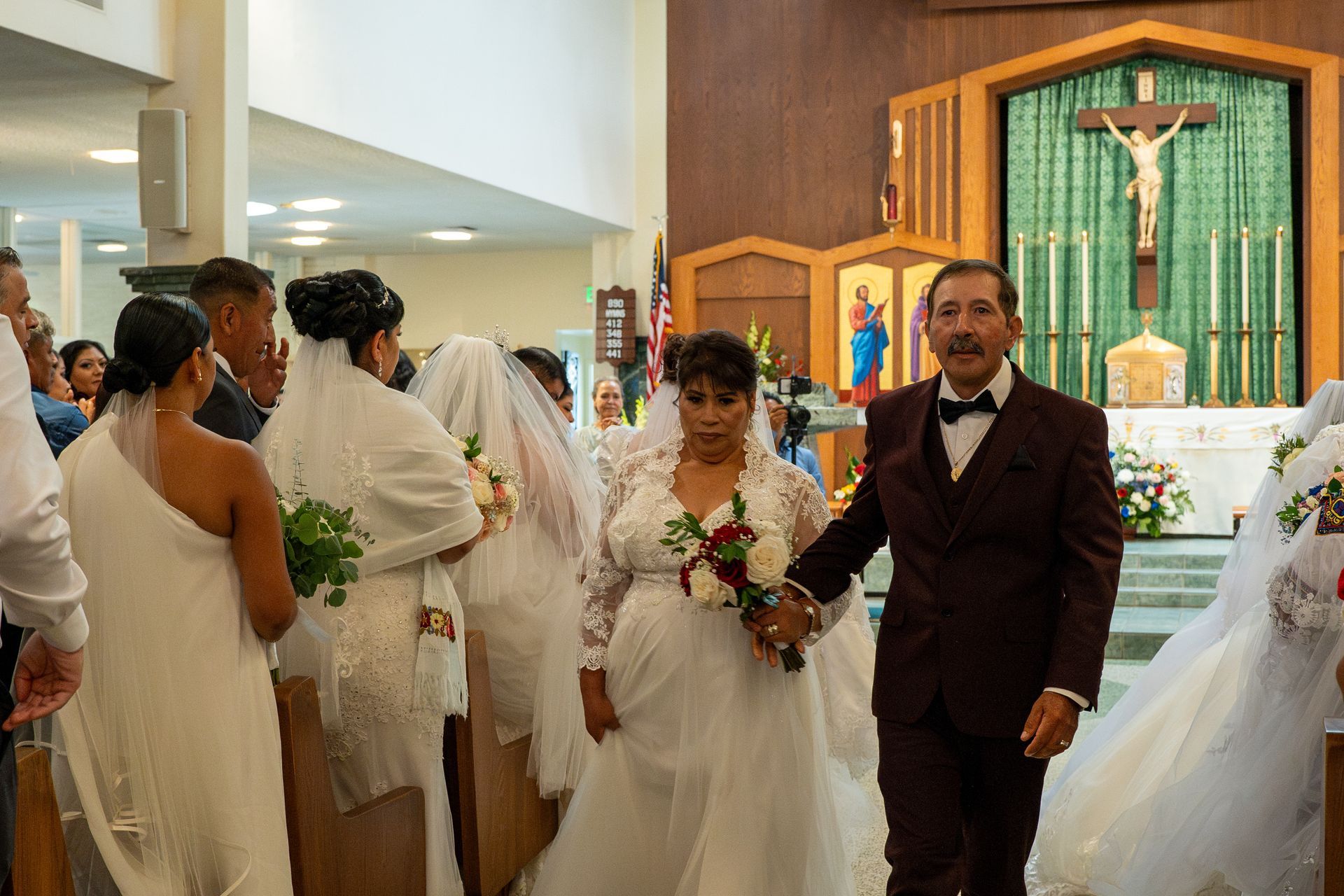 Wedding procession inside a church, with bride, groom, and attendants walking down the aisle.
