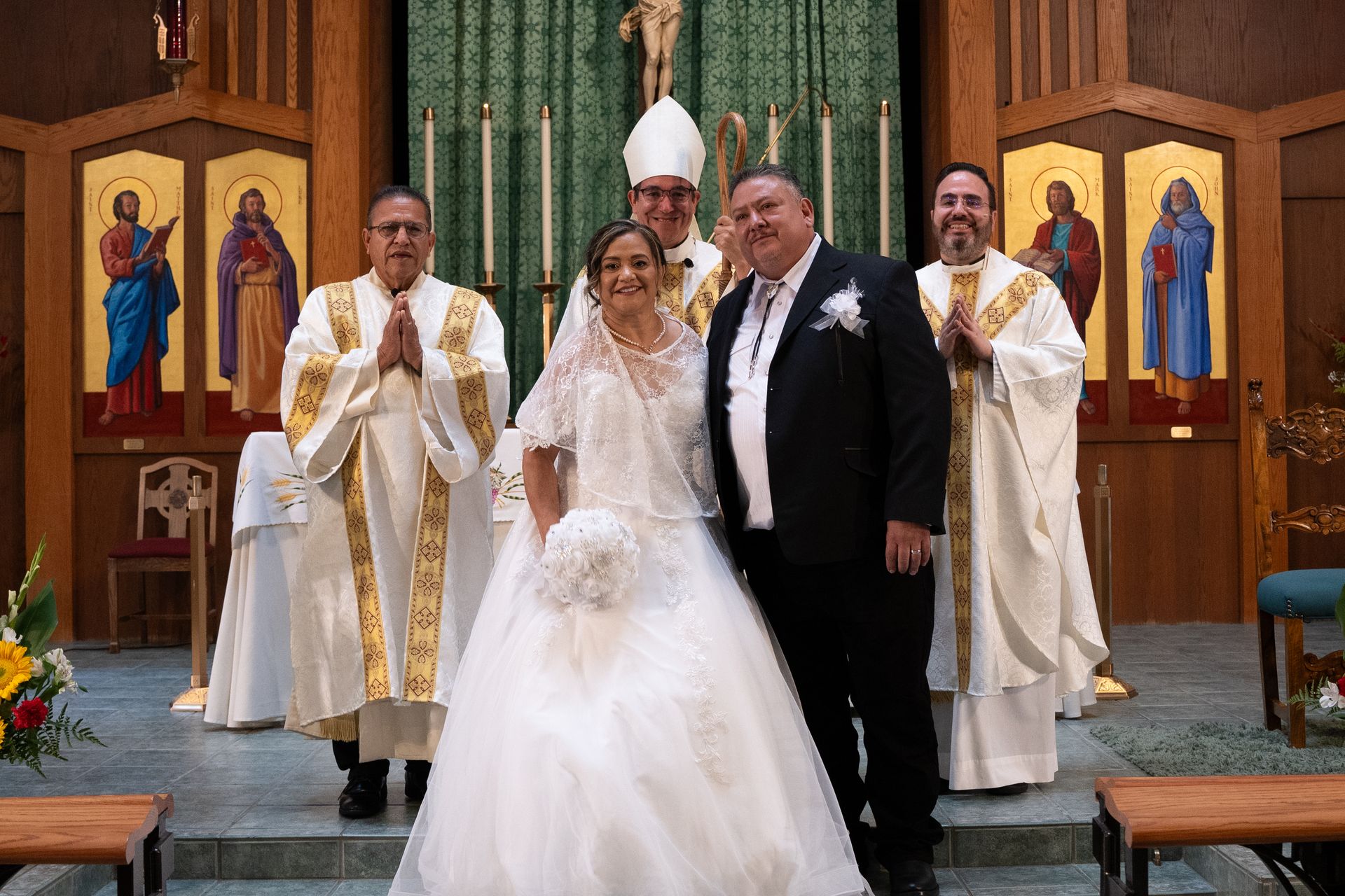 Wedding couple standing with four clergy members in a church sanctuary.