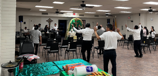 People standing with raised arms in a community hall during a group exercise session