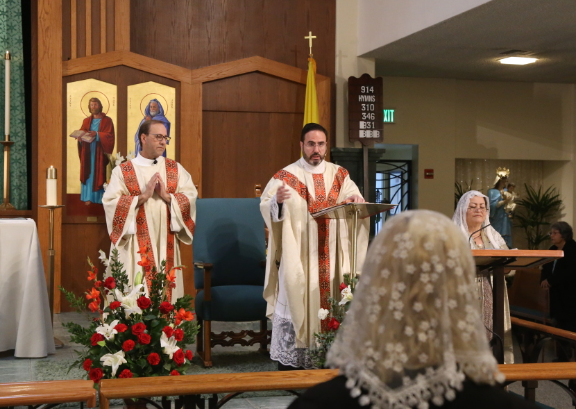 Two clergy in white robes stand at a church altar during a service.