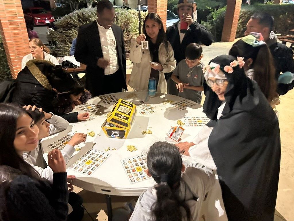 People gathered around a round table playing a colorful board game indoors.