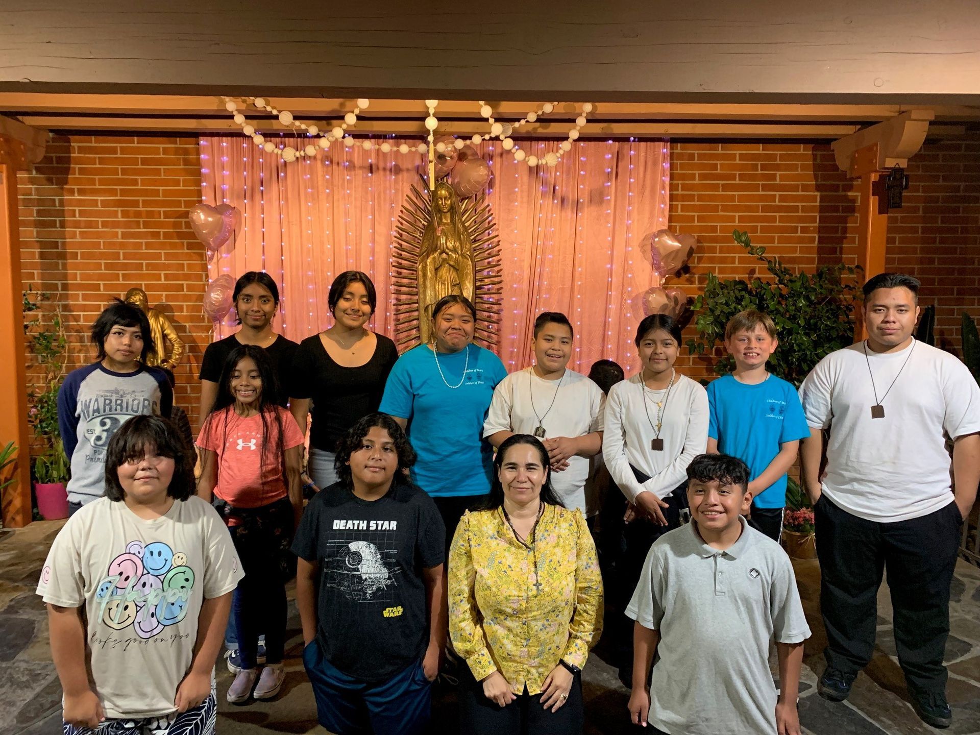 Group of people posing indoors in front of a pink and gold decorative backdrop