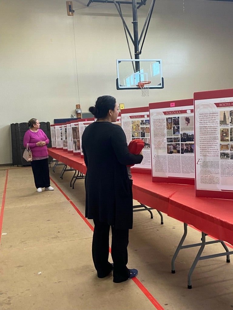 People viewing poster boards at a school science fair in a gymnasium