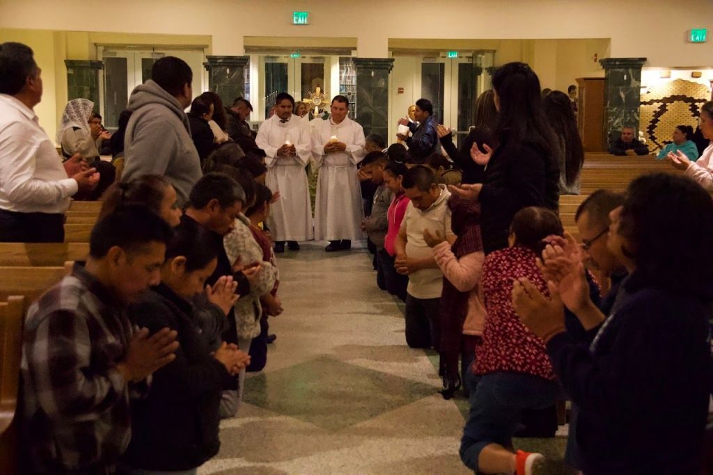 People standing in a hallway applauding as a choir performs at the back.