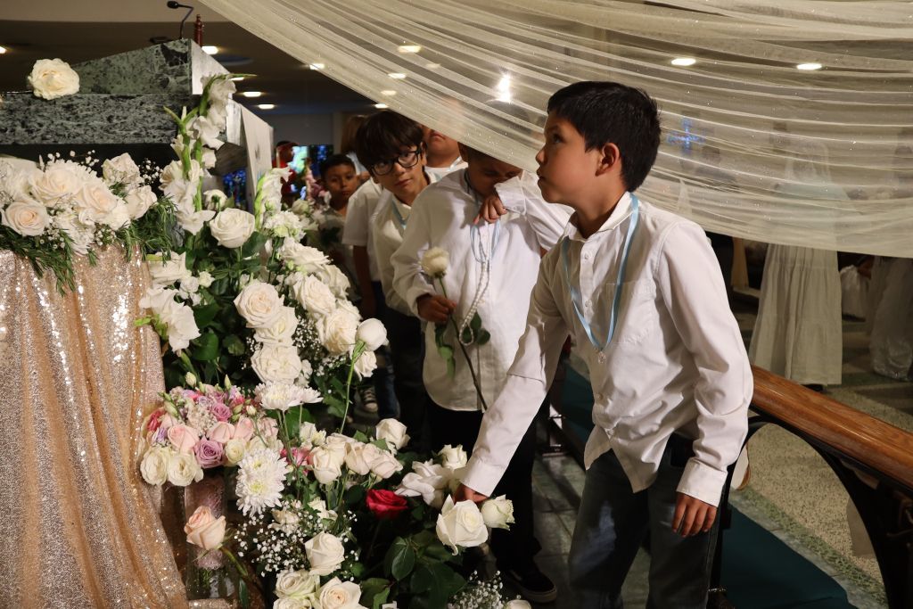 People standing beside a white floral arrangement under draped fabric at an indoor event