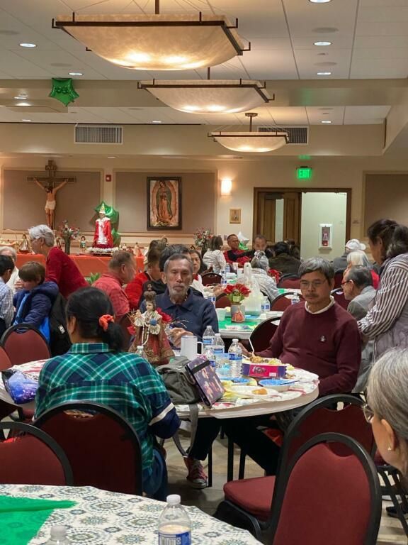 People seated at tables in a decorated banquet hall, sharing a festive meal.