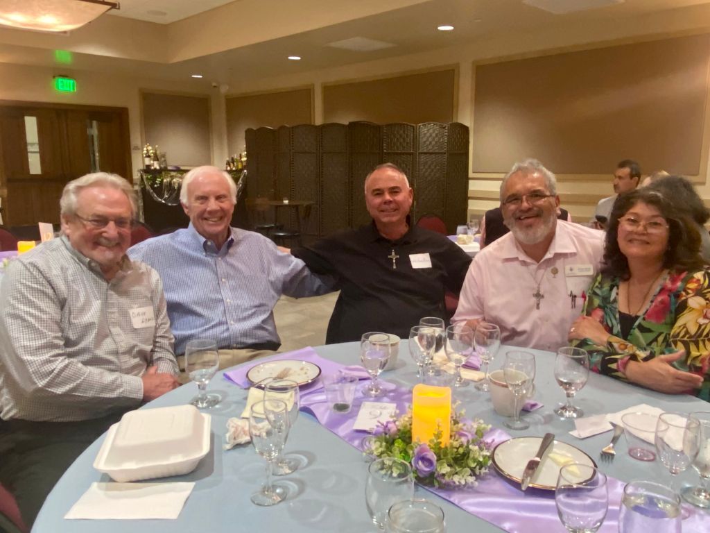 Five people smiling around a banquet table with purple decorations in a restaurant dining room