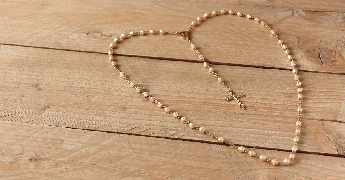 Rosary beads arranged in a heart shape on a wooden surface