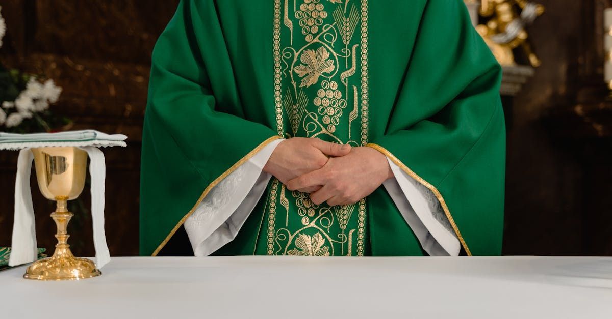 Priest in green vestments stands at the altar beside a gold chalice and white cloth