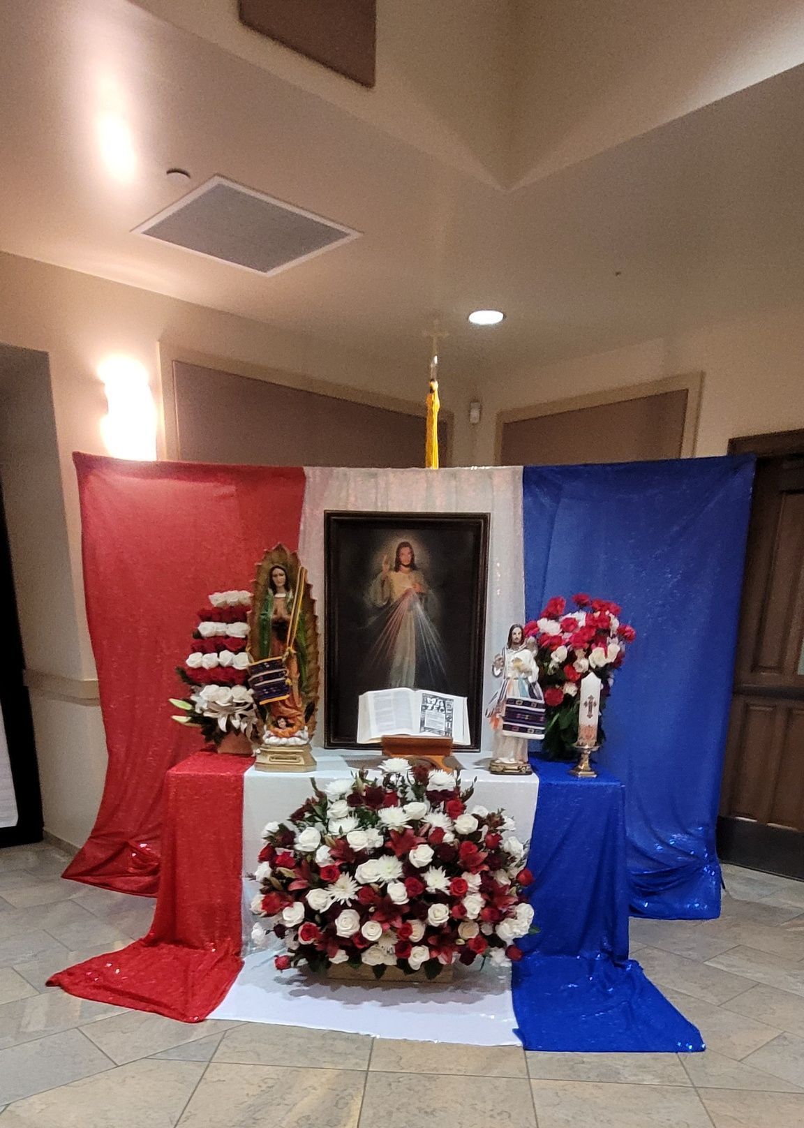Memorial altar with framed portrait, white and red flowers, and draped red, white, and blue fabric