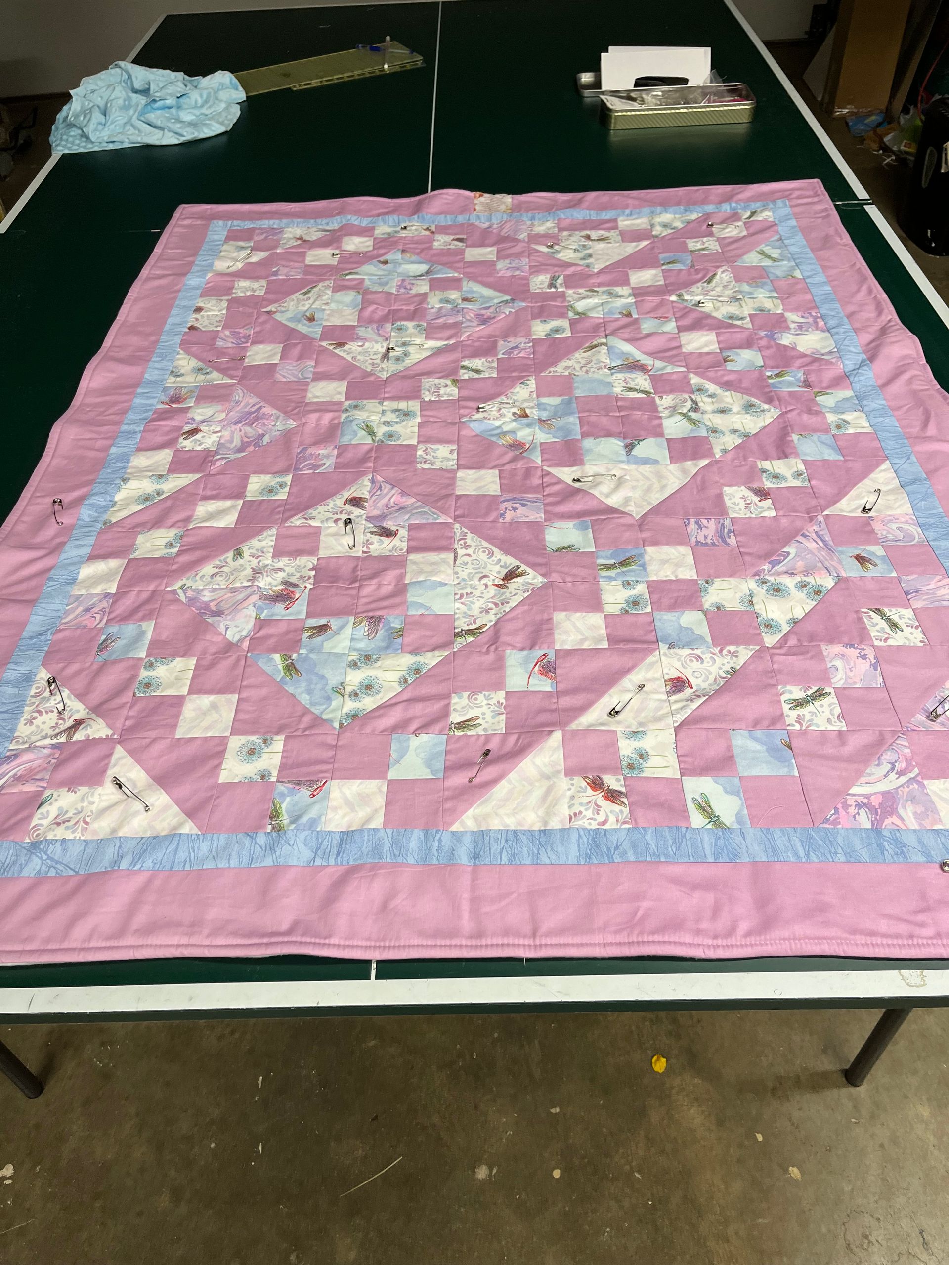 Pink and blue patchwork quilt laid flat on a table outdoors