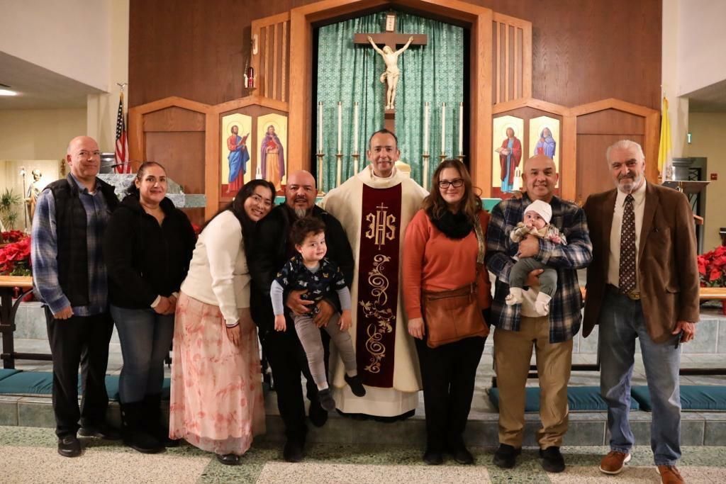 Group of people standing in a church before an altar and crucifix, posing for a photo.