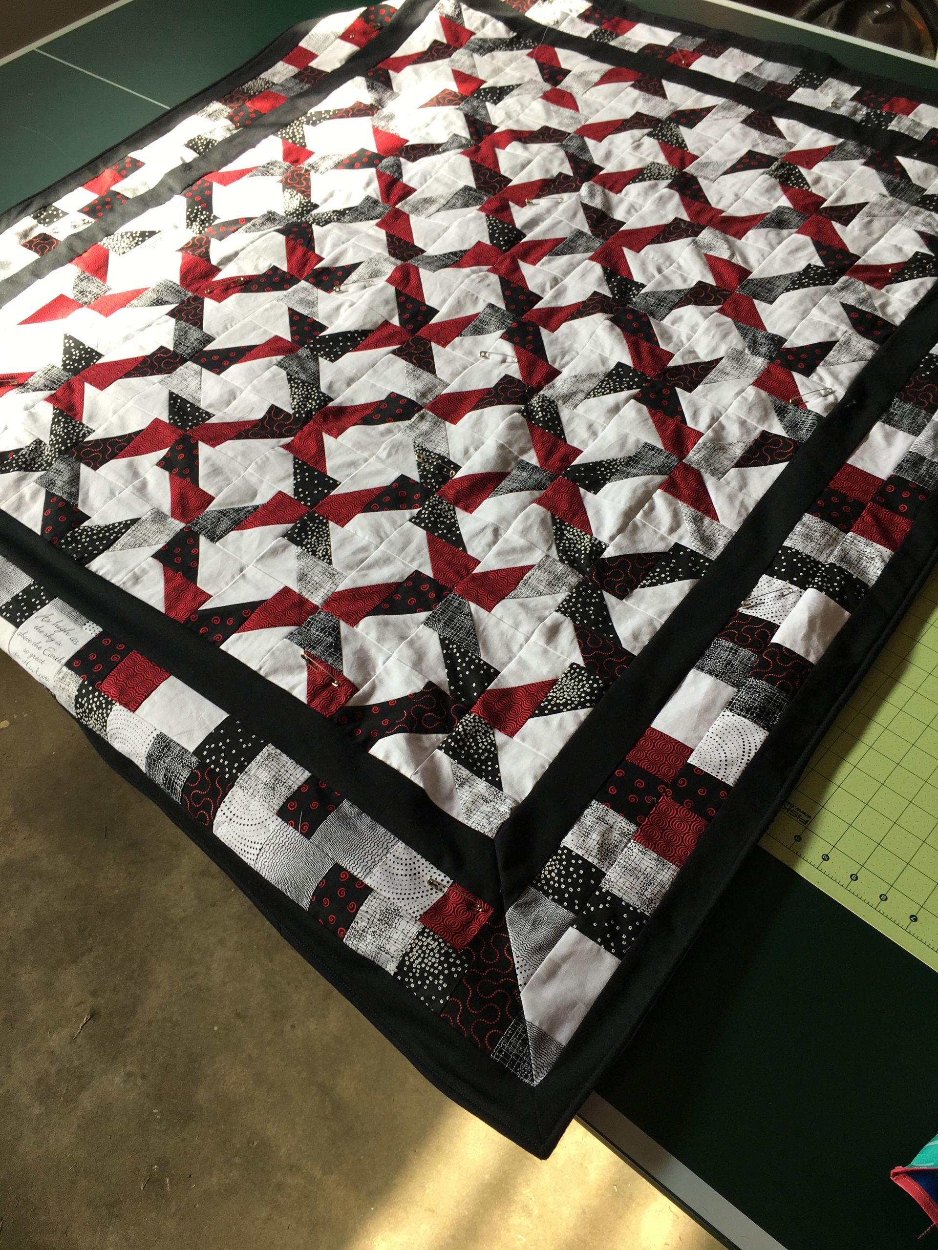 Black, white, and red quilt laid flat on a worktable, viewed from above.