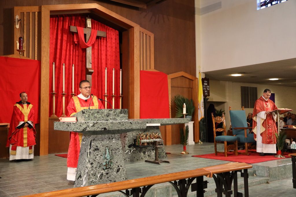 Three clergy in red vestments stand at a church altar during a service