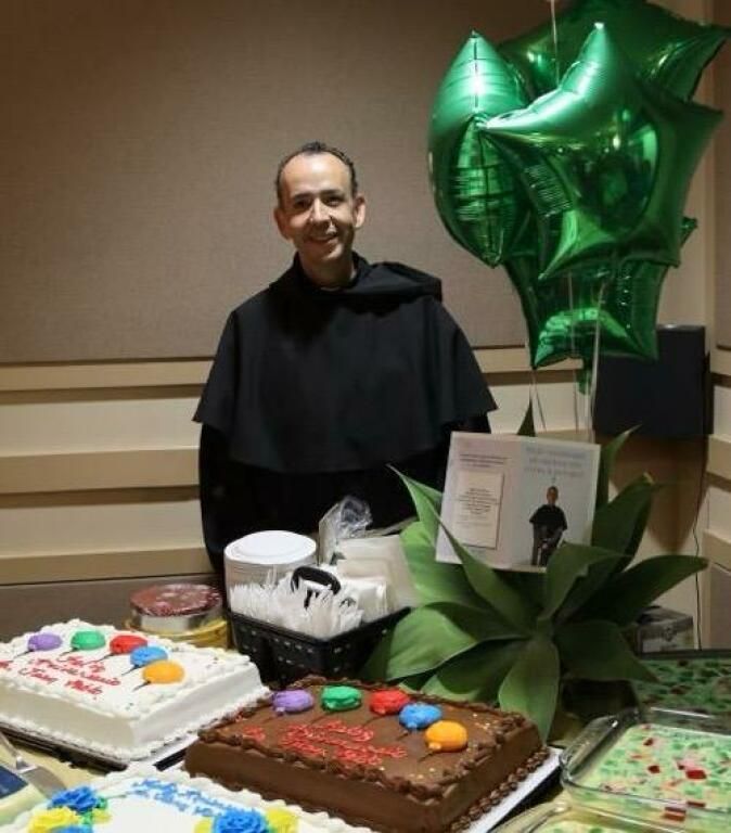 Person standing behind a birthday cake table with green star balloons and a framed card