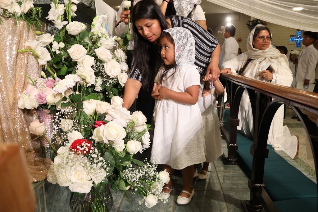 Woman and child viewing white and pink floral arrangements at an indoor event