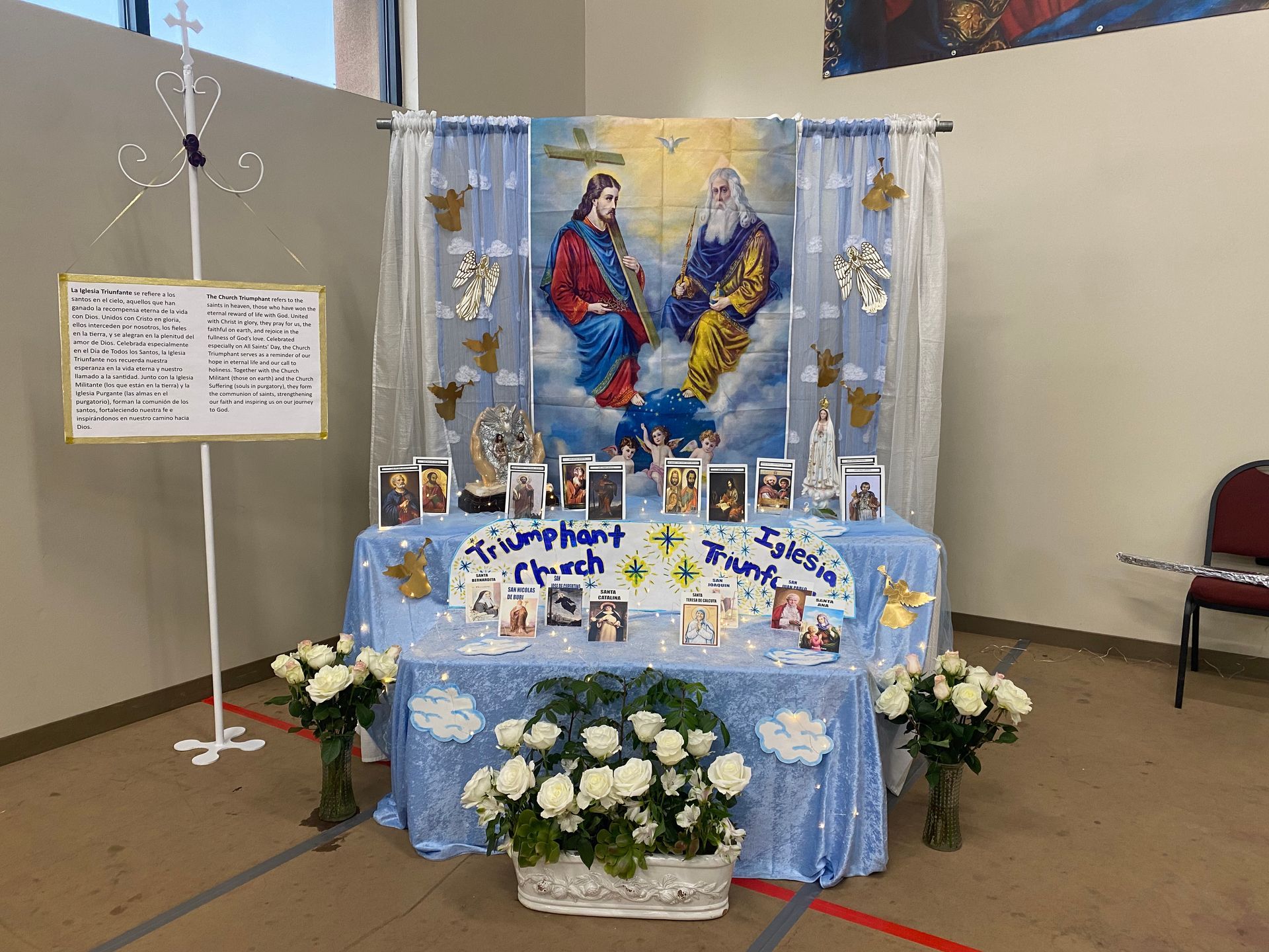 Religious altar display with blue decorations, flowers, candles, and a central devotional image.