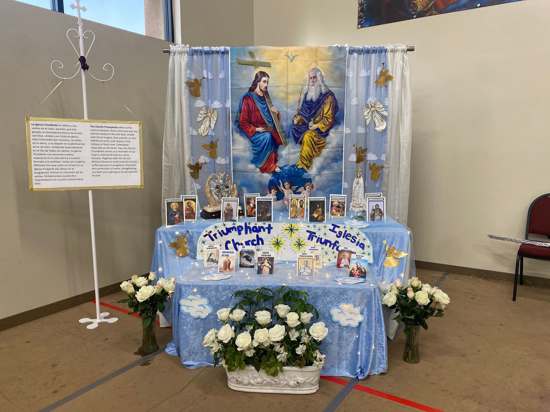 Decorated religious altar with blue cloth, flowers, candles, and saint images in a room