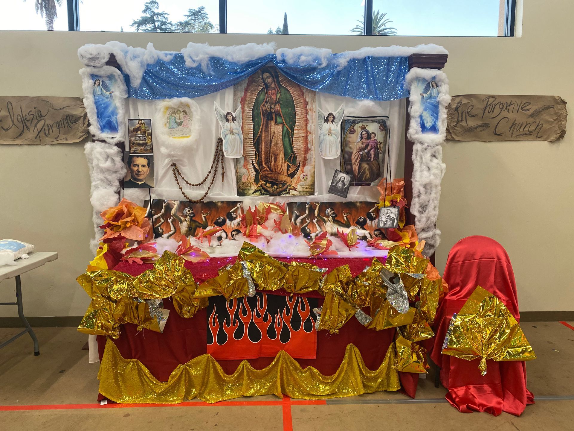 Decorated altar with Hindu deities, flowers, garlands, and colorful fabrics on a table indoors
