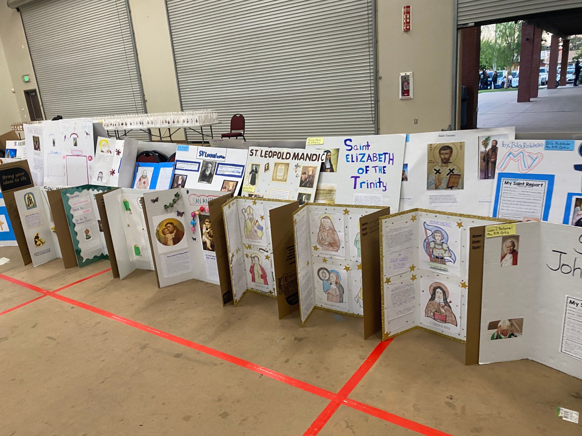 Row of student poster boards displayed indoors on easels, with colorful drawings and handwritten notes.