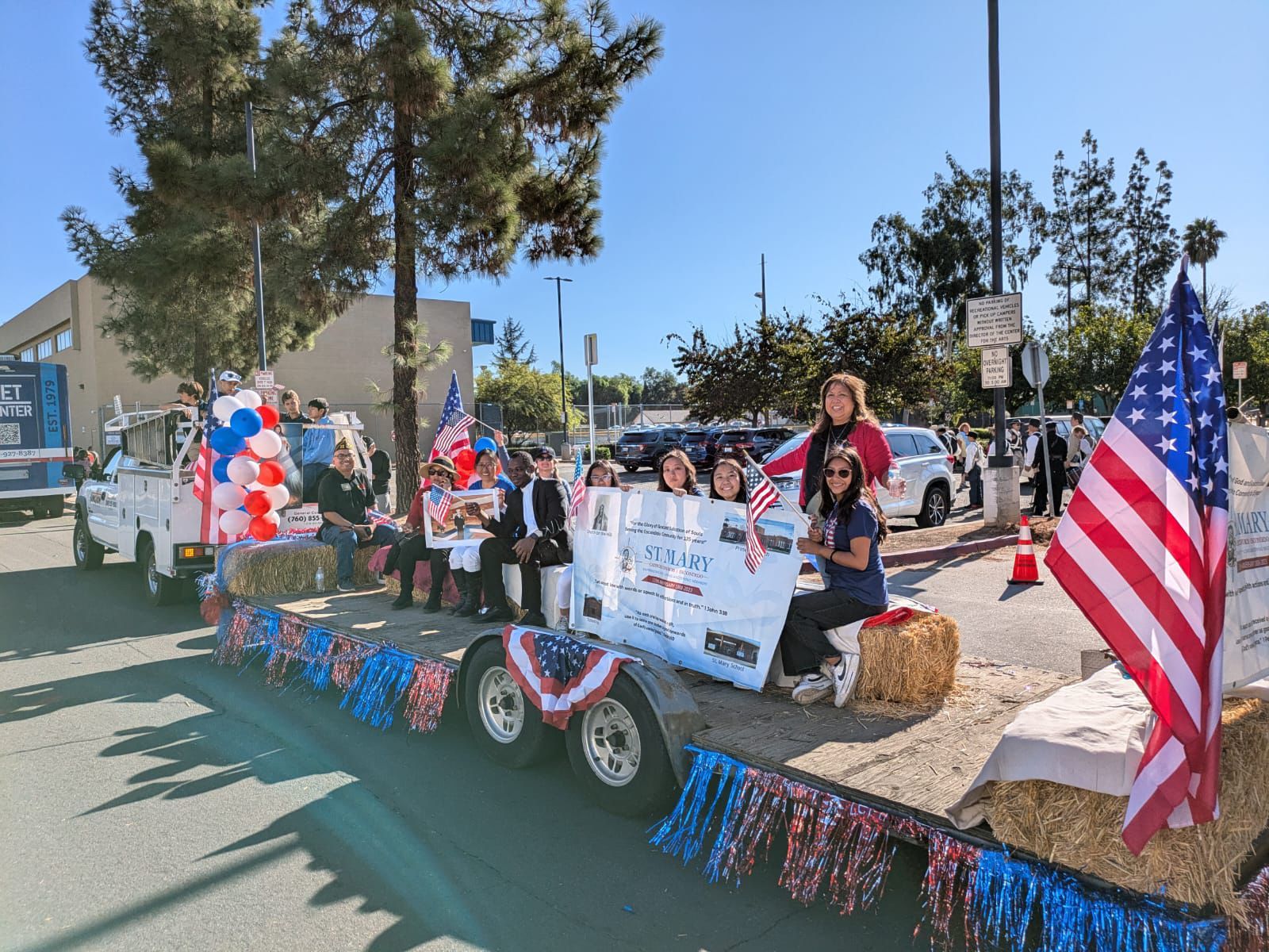 Decorated parade float with American flags and people standing outdoors on a sunny street