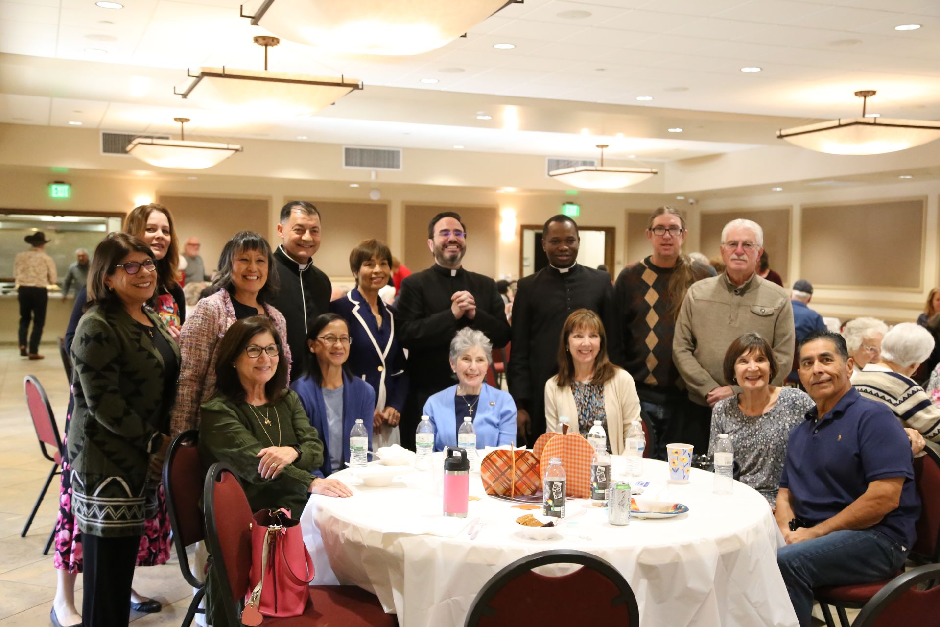Group of people posing around a banquet table in a warmly lit event hall