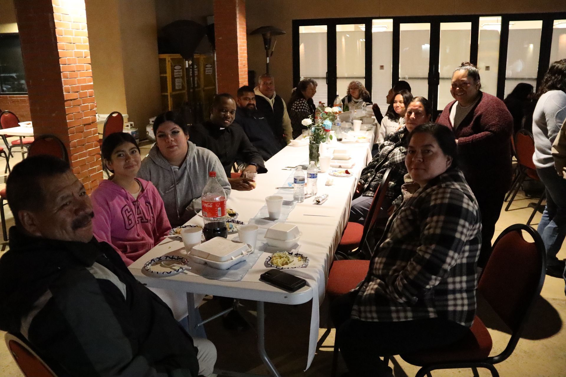 People seated at a long dining table in a warmly lit restaurant, looking toward the camera.