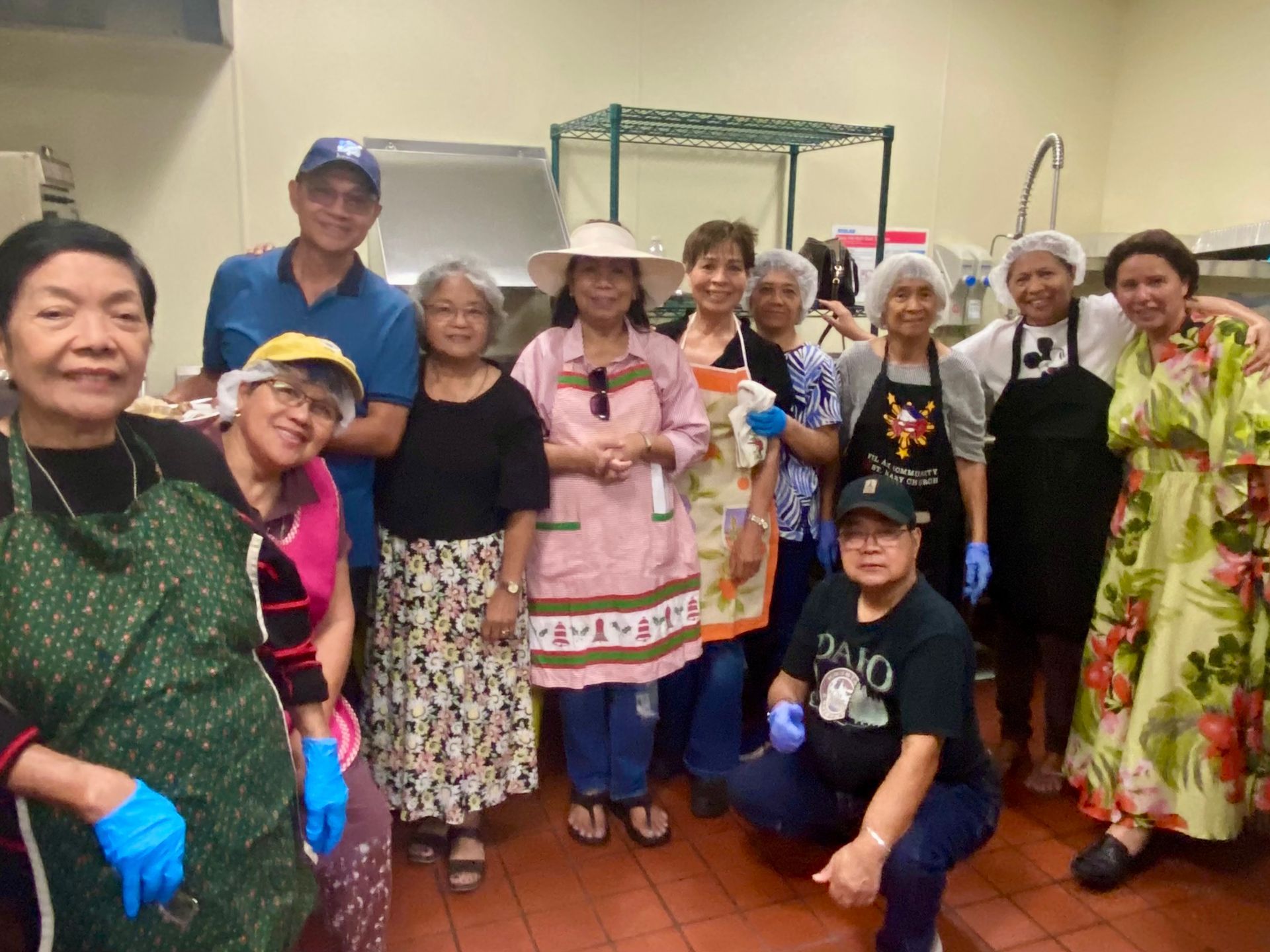 Group of people in costumes posing indoors, some wearing hats and colorful outfits, smiling at the camera.