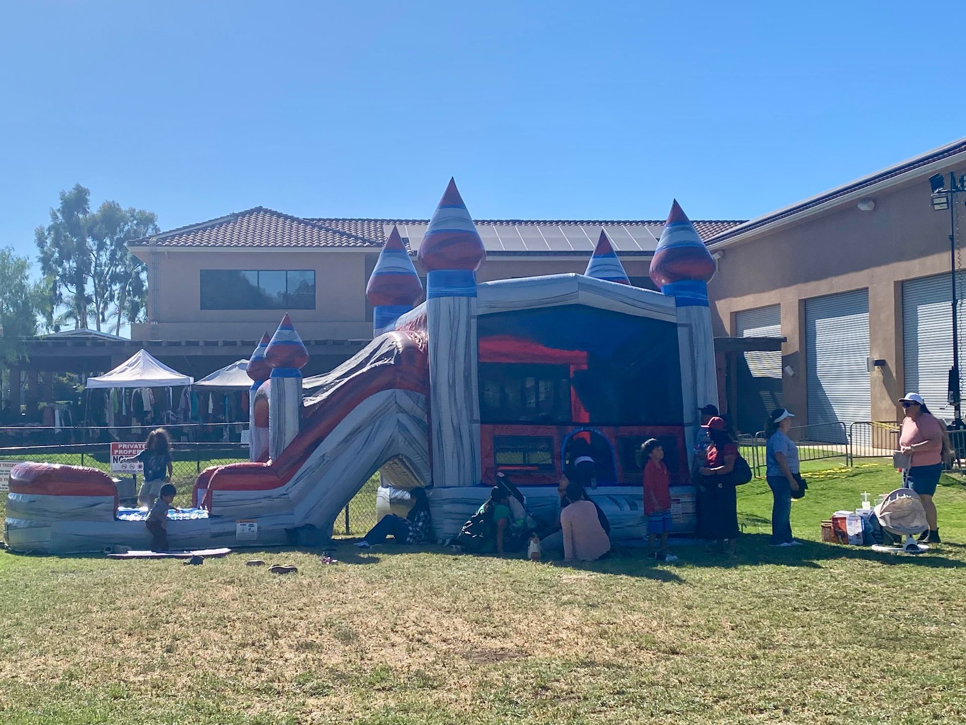 Inflatable bounce house with slide and children at a sunny outdoor event