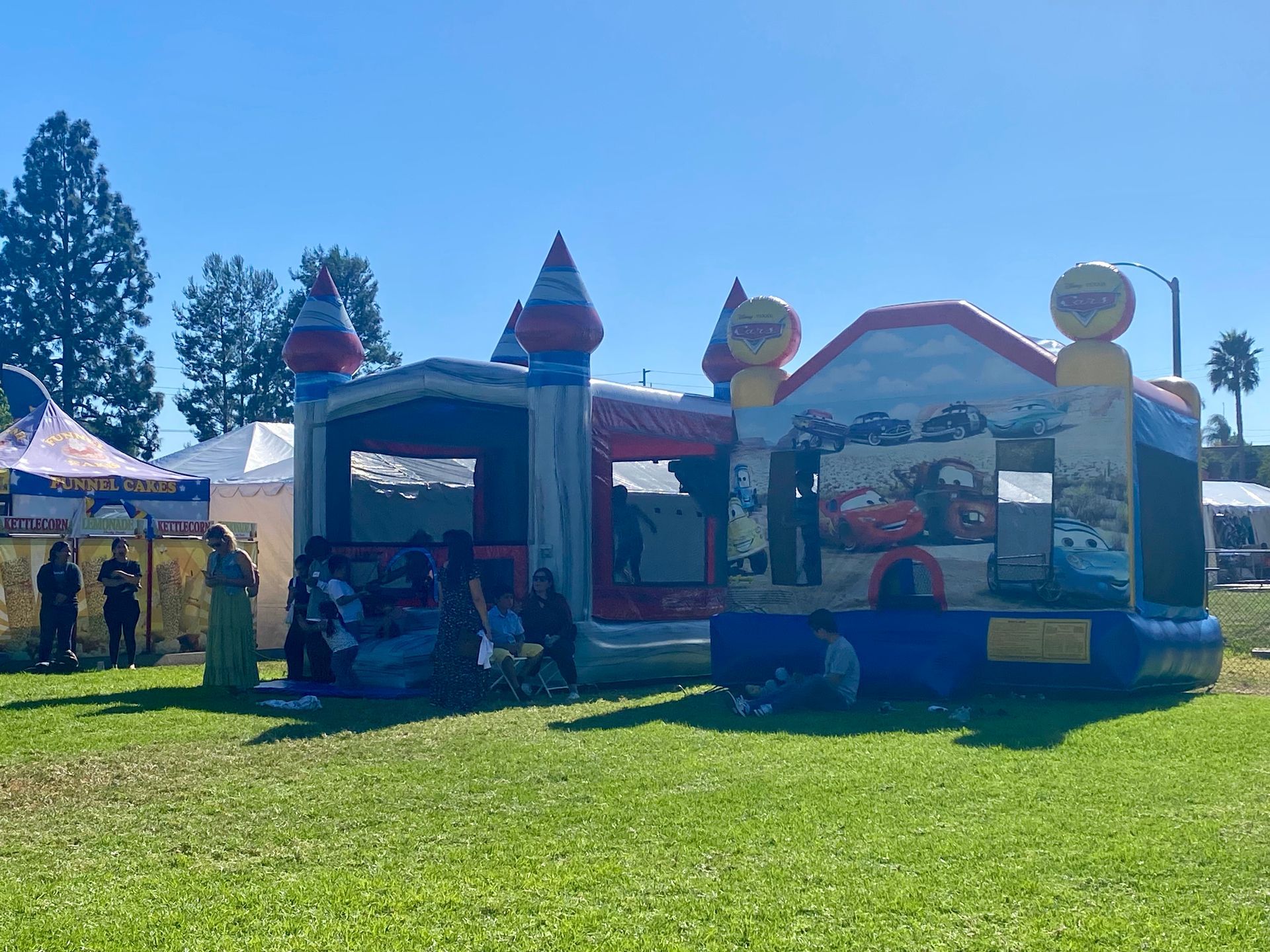Colorful inflatable bounce house and slide at a sunny outdoor fair on a grassy field