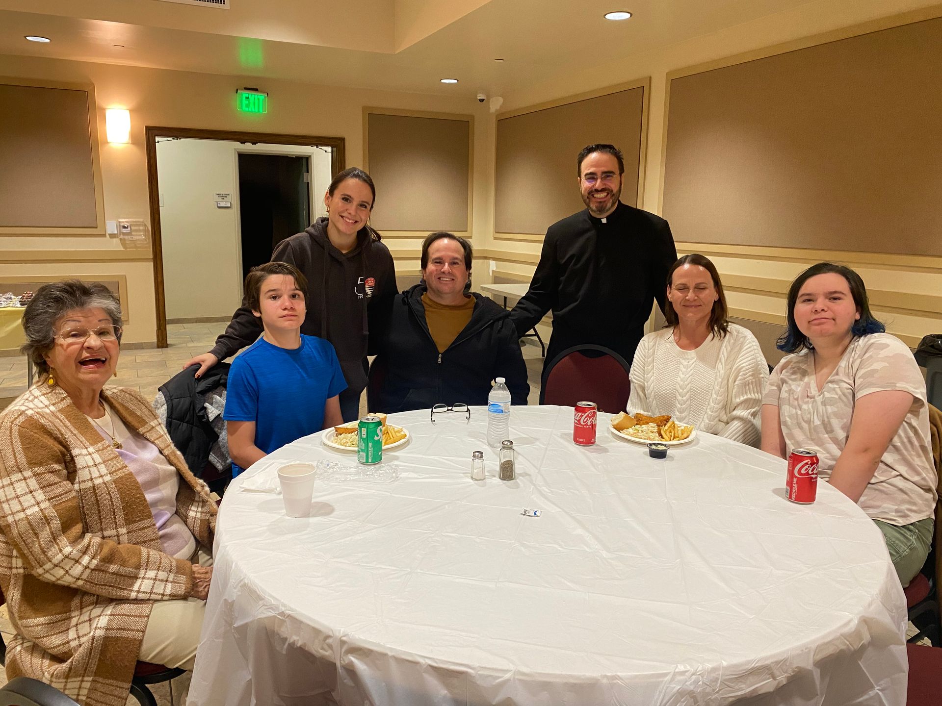 Group seated around a round table in a banquet room, smiling at the camera.