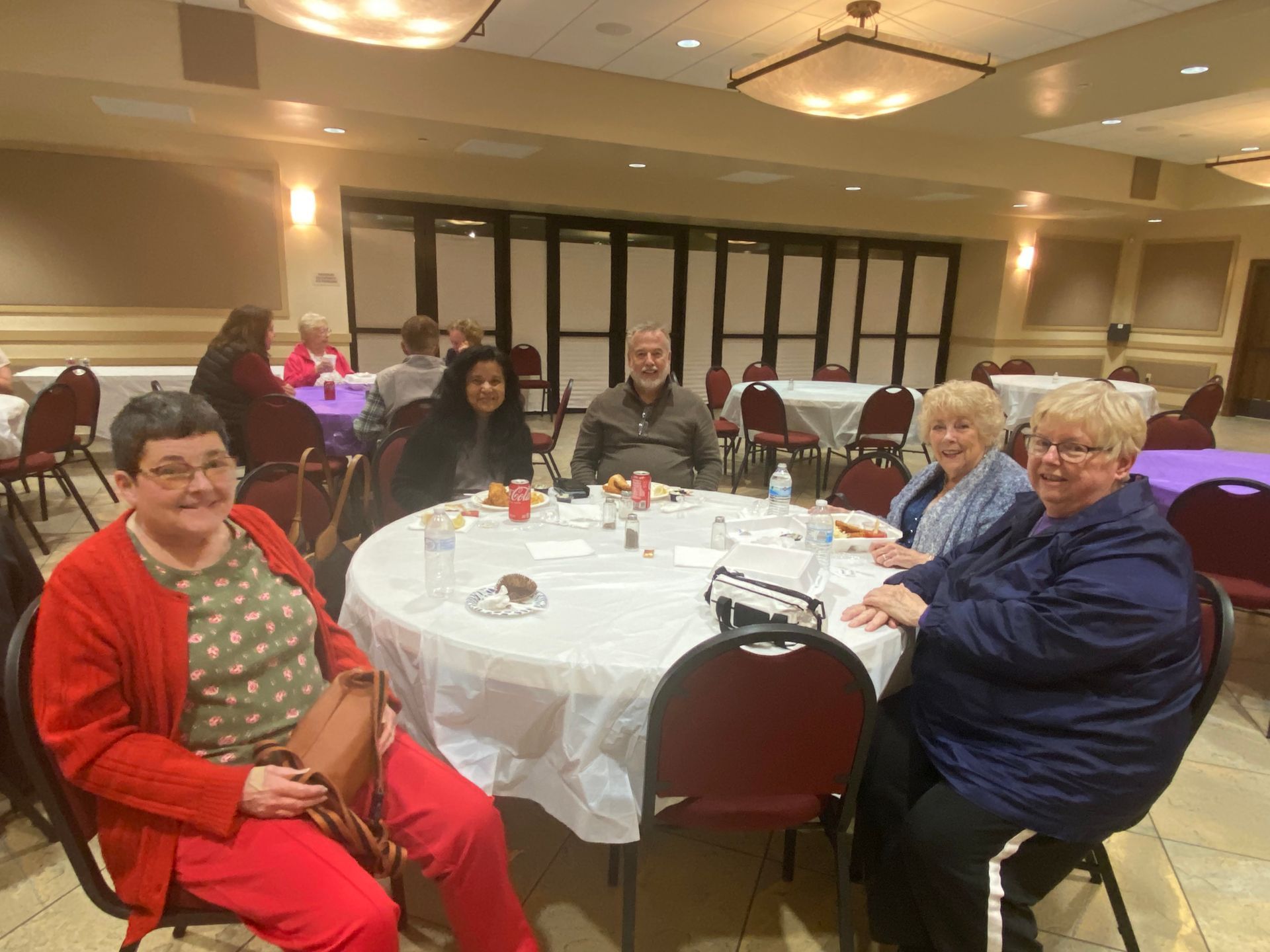 People seated around a round table at a banquet hall, smiling and chatting during a social gathering