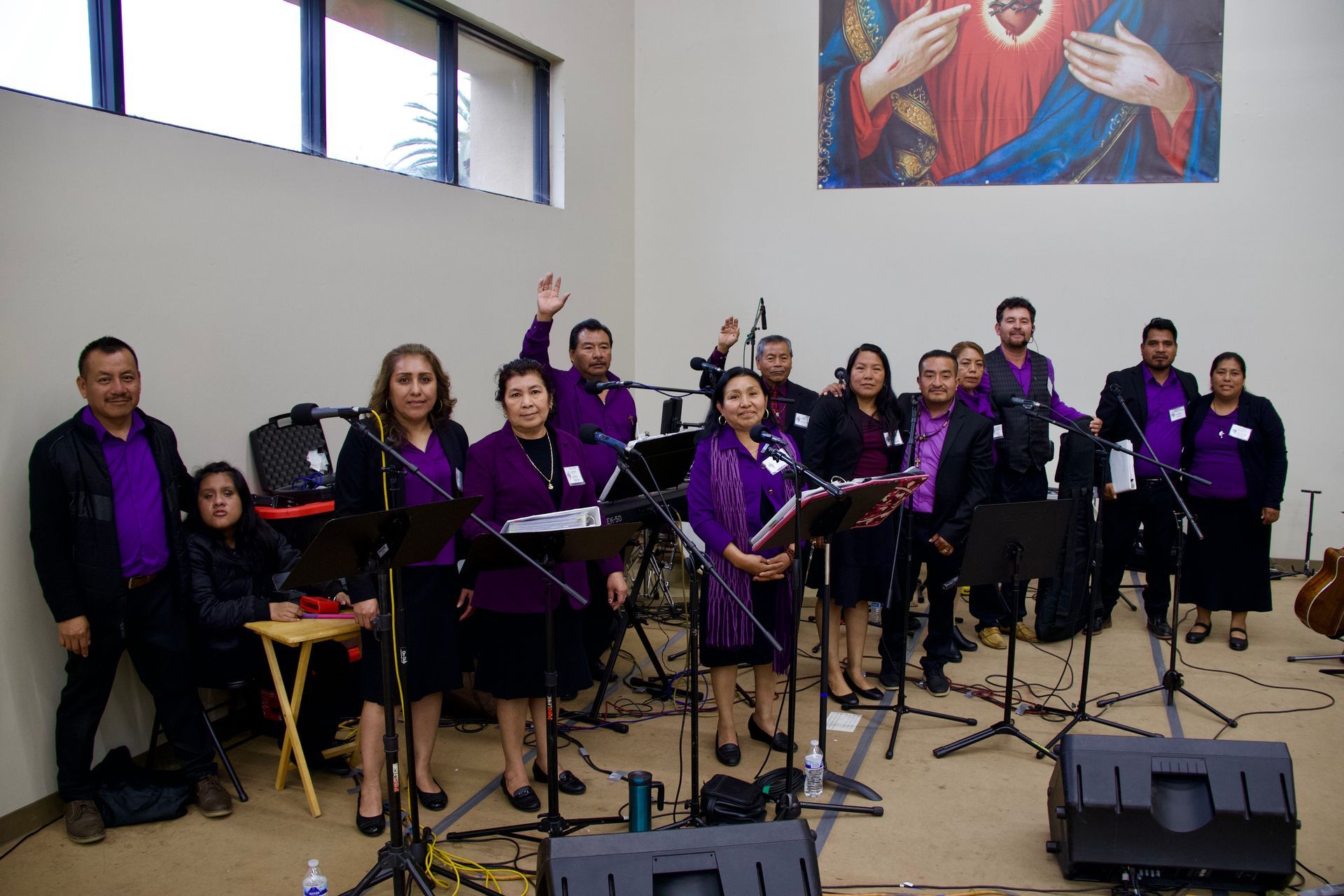 Choir in purple robes standing with microphones in a church hall