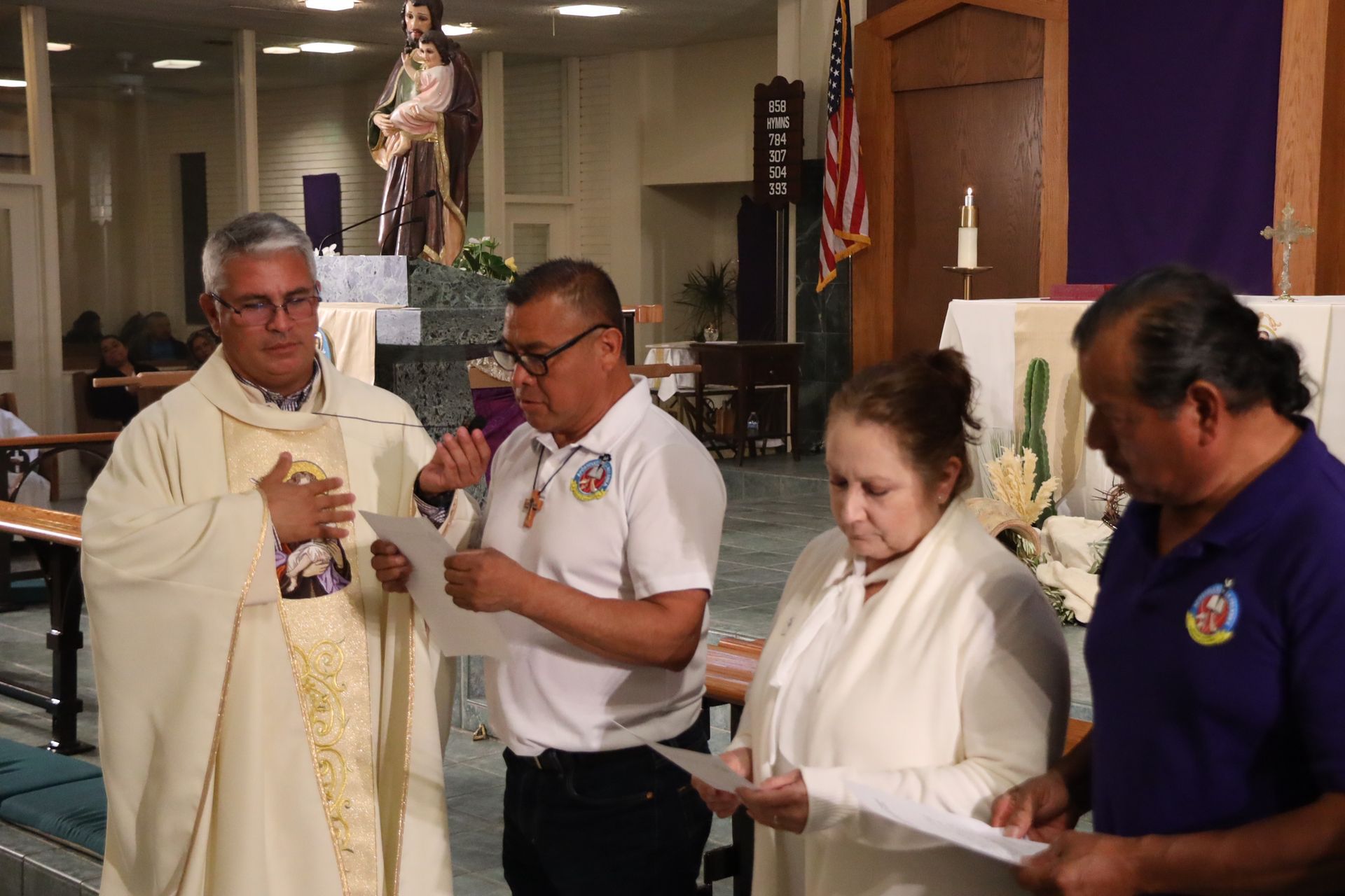 People holding candles and papers during a church ceremony inside a chapel