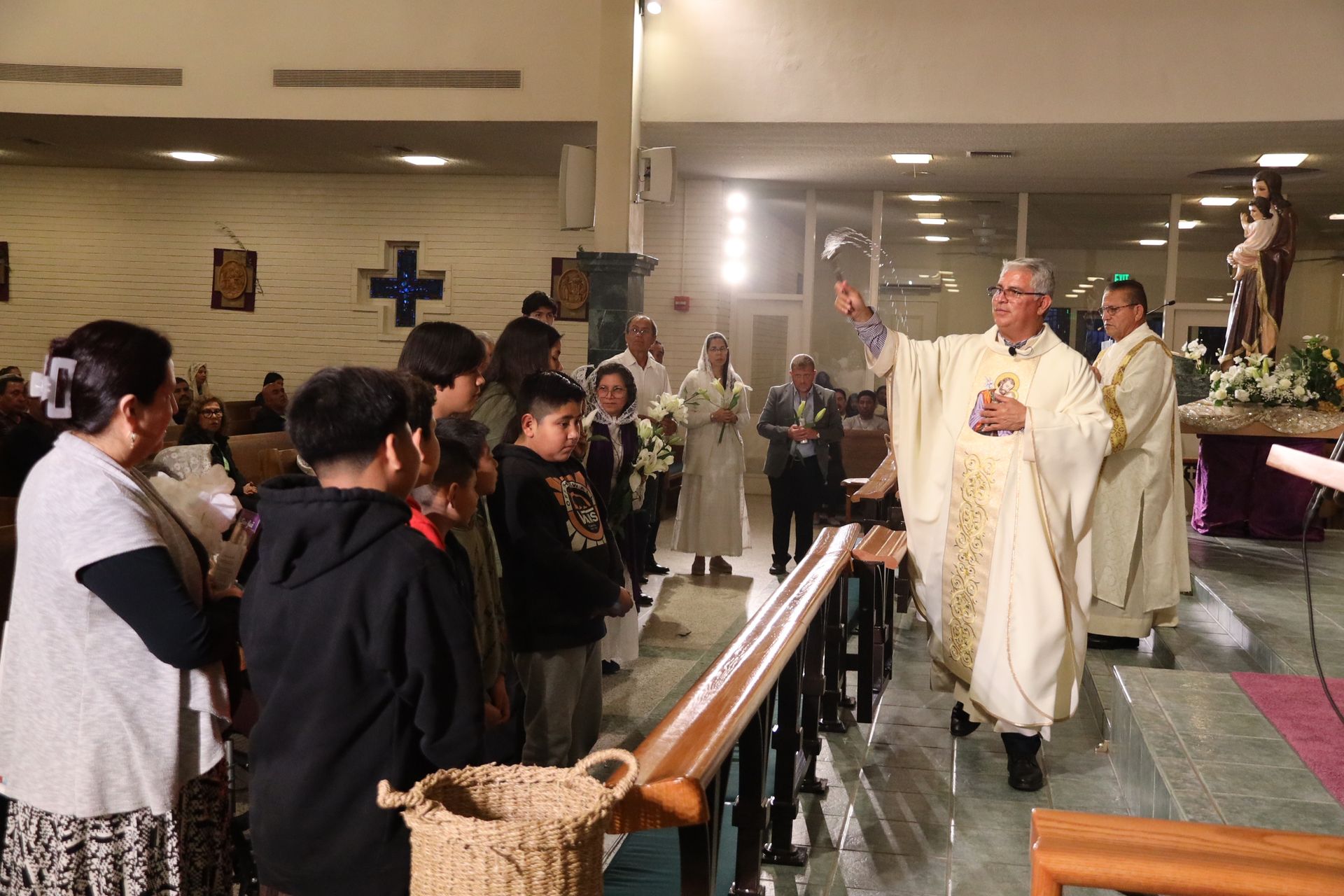 Priest processing down church aisle during a service, with congregants standing on either side