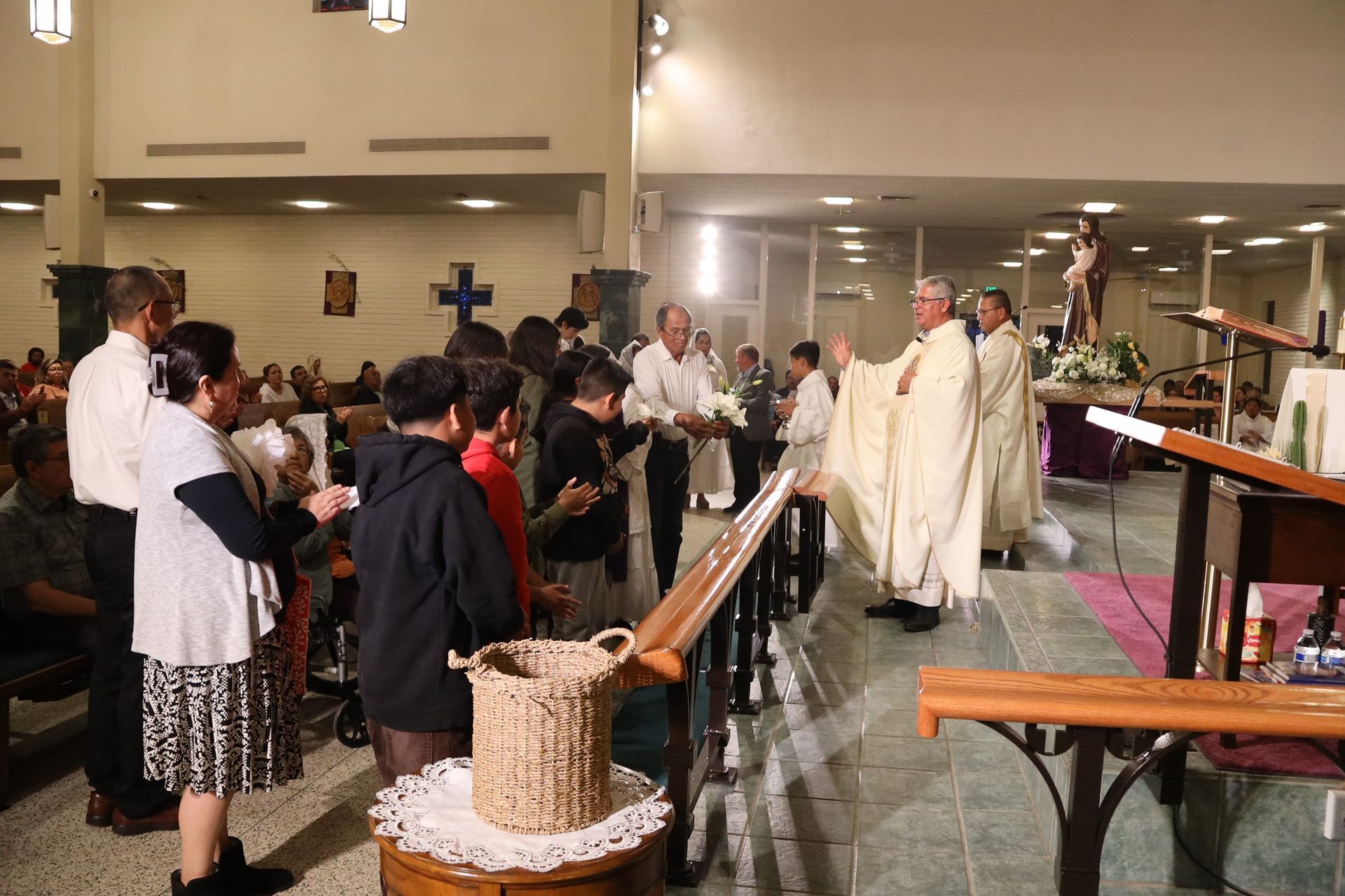 Church congregation standing as clergy in white robes process down the aisle during a service