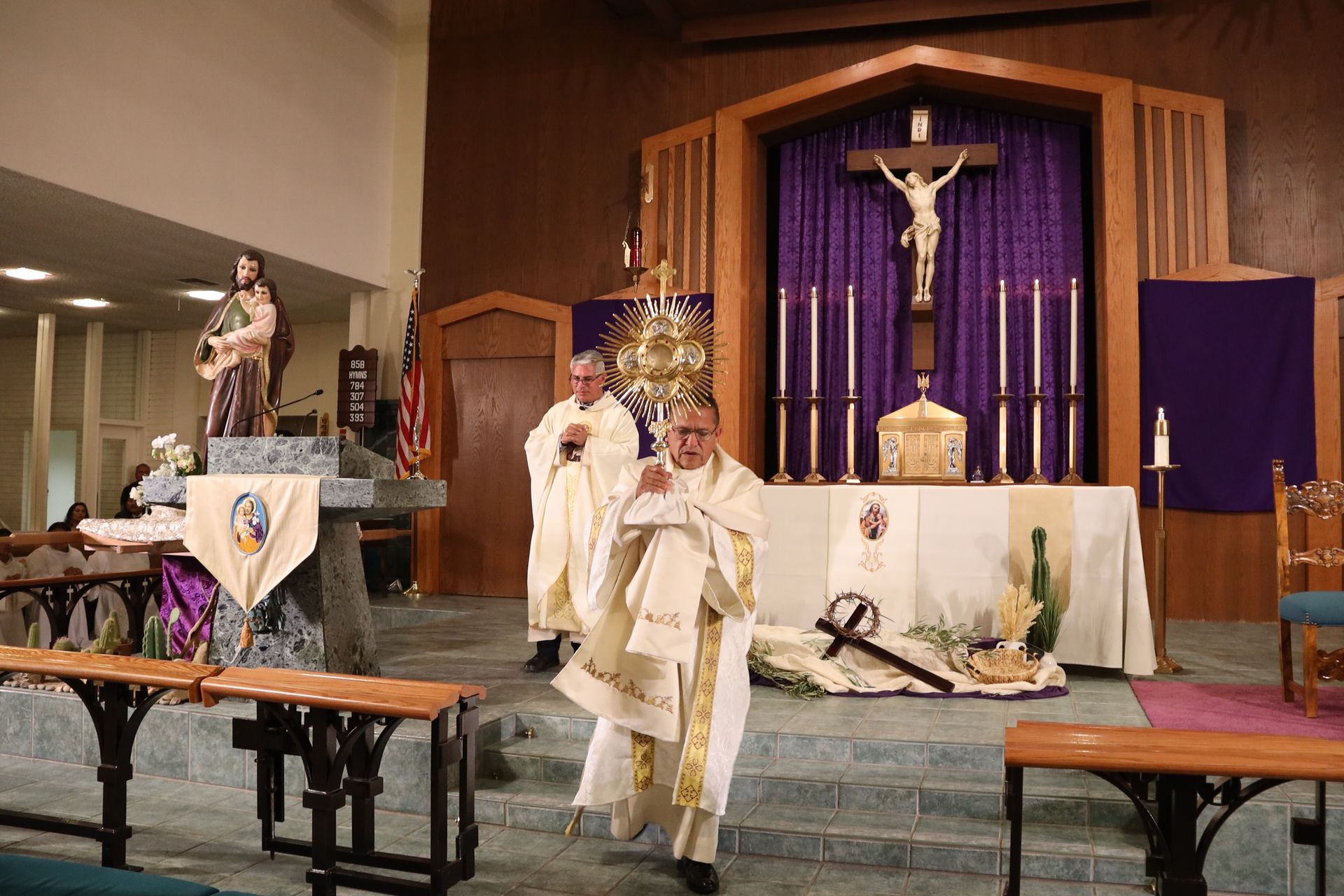Priests processing in a church sanctuary before a purple altar with a crucifix
