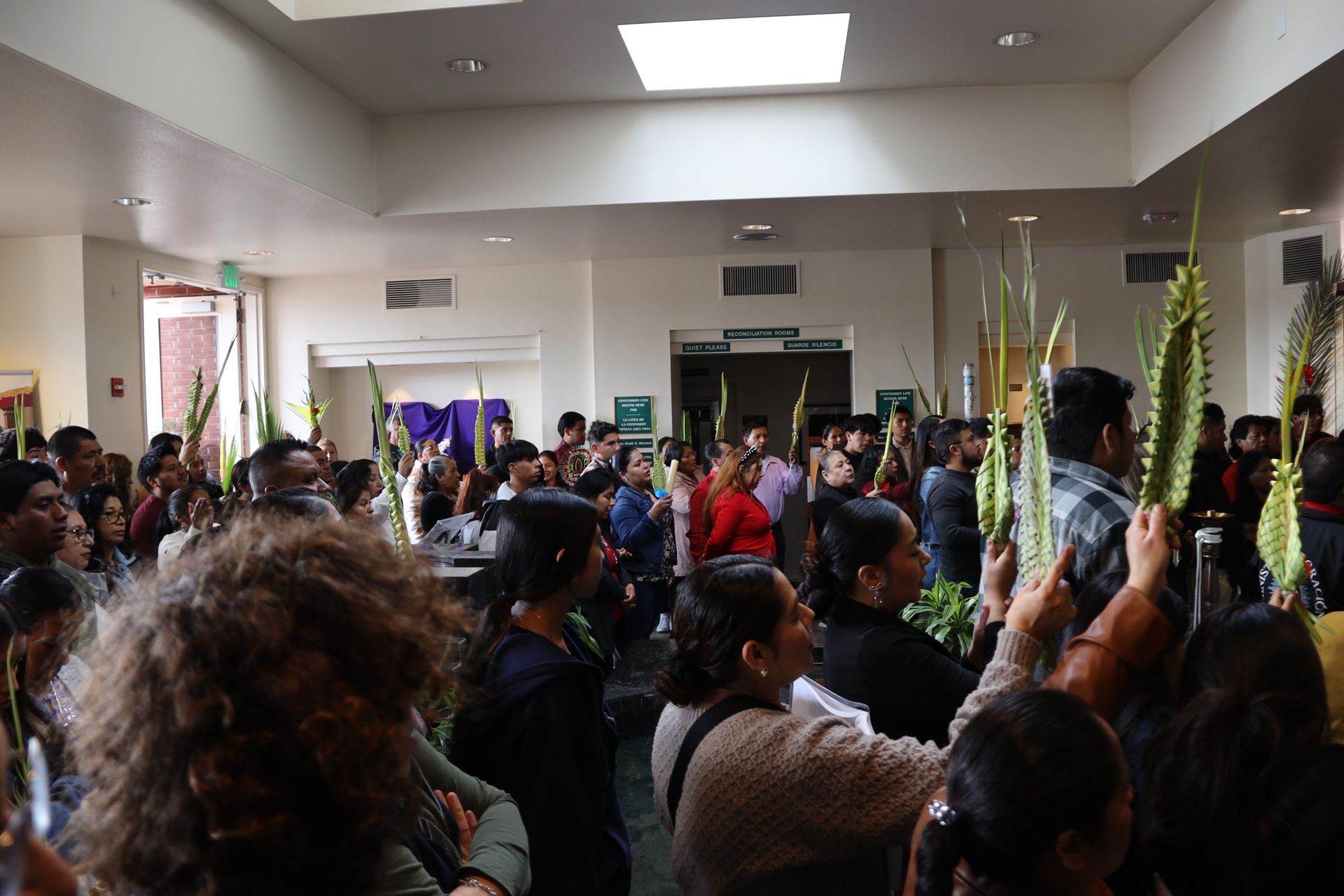 Crowded indoor gathering with people standing and holding up phones in a hall