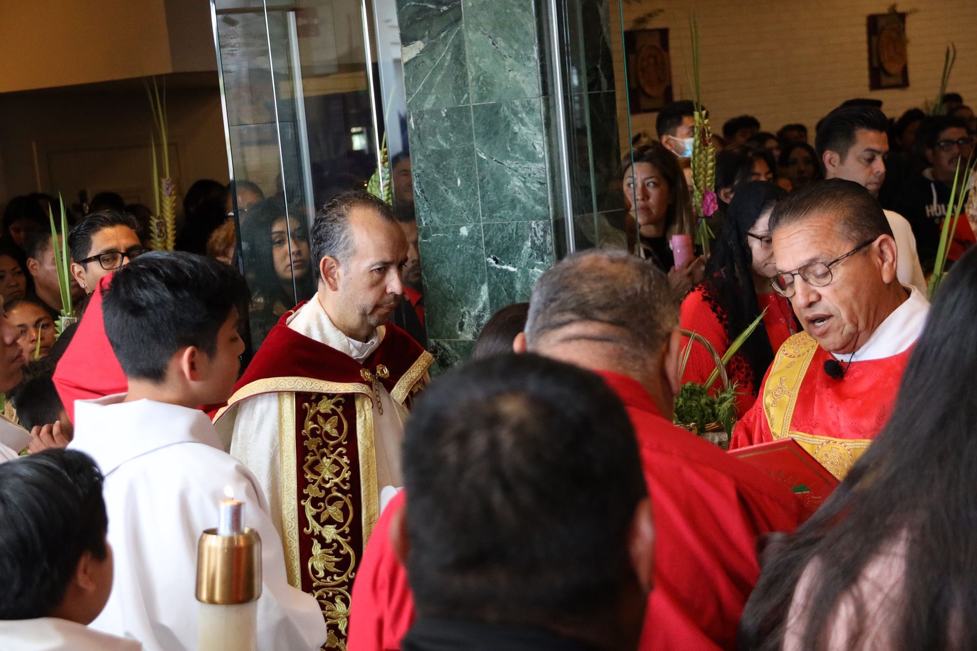 Clergy in red and white vestments gather indoors during a religious ceremony