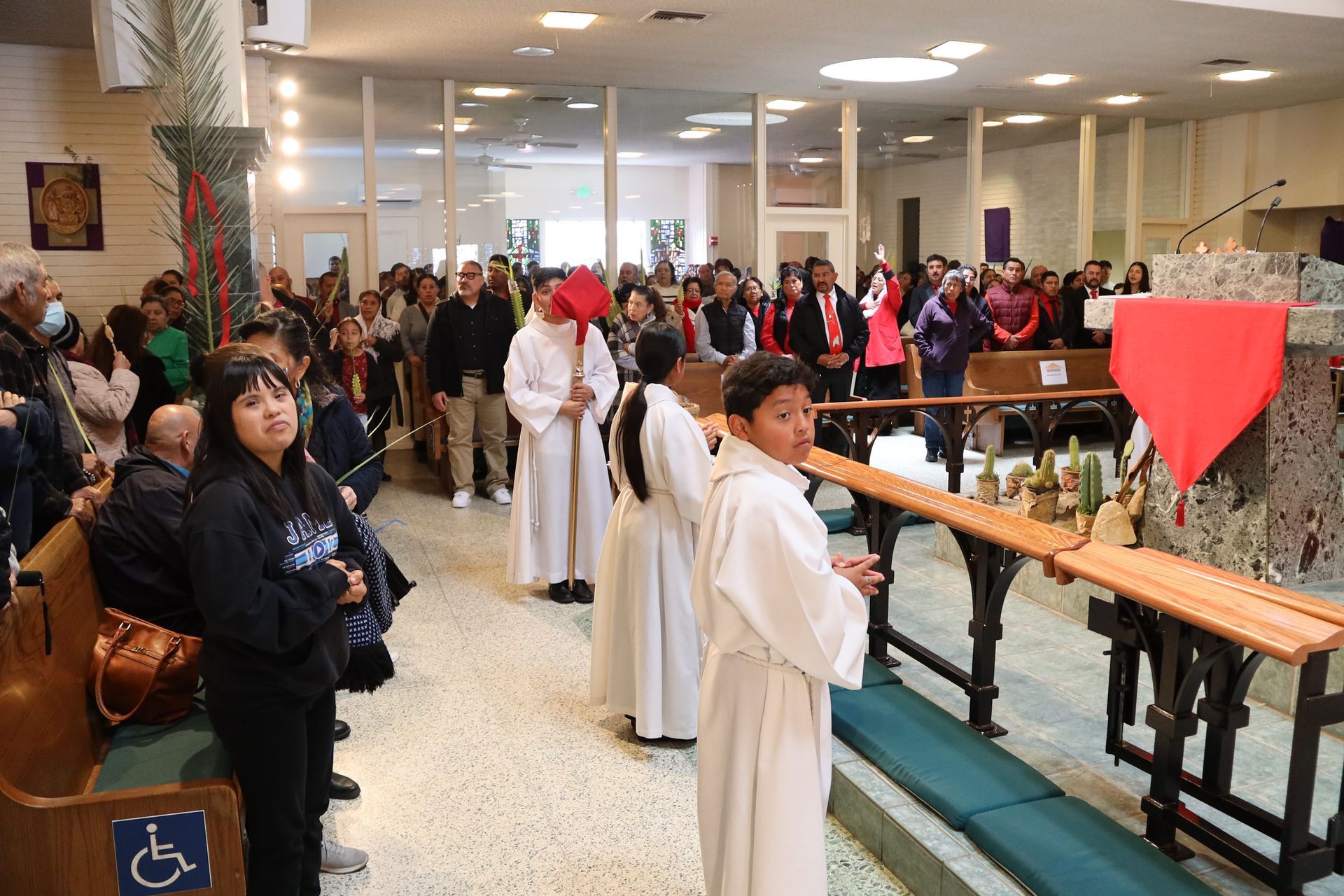 People in white robes and a crowd gathered inside a church during a religious ceremony