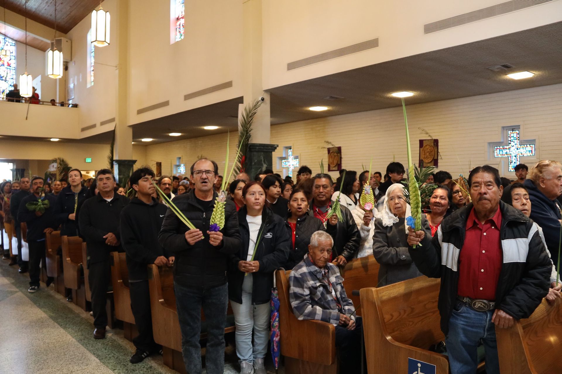 People standing in church pews during a service, holding candles and facing forward.