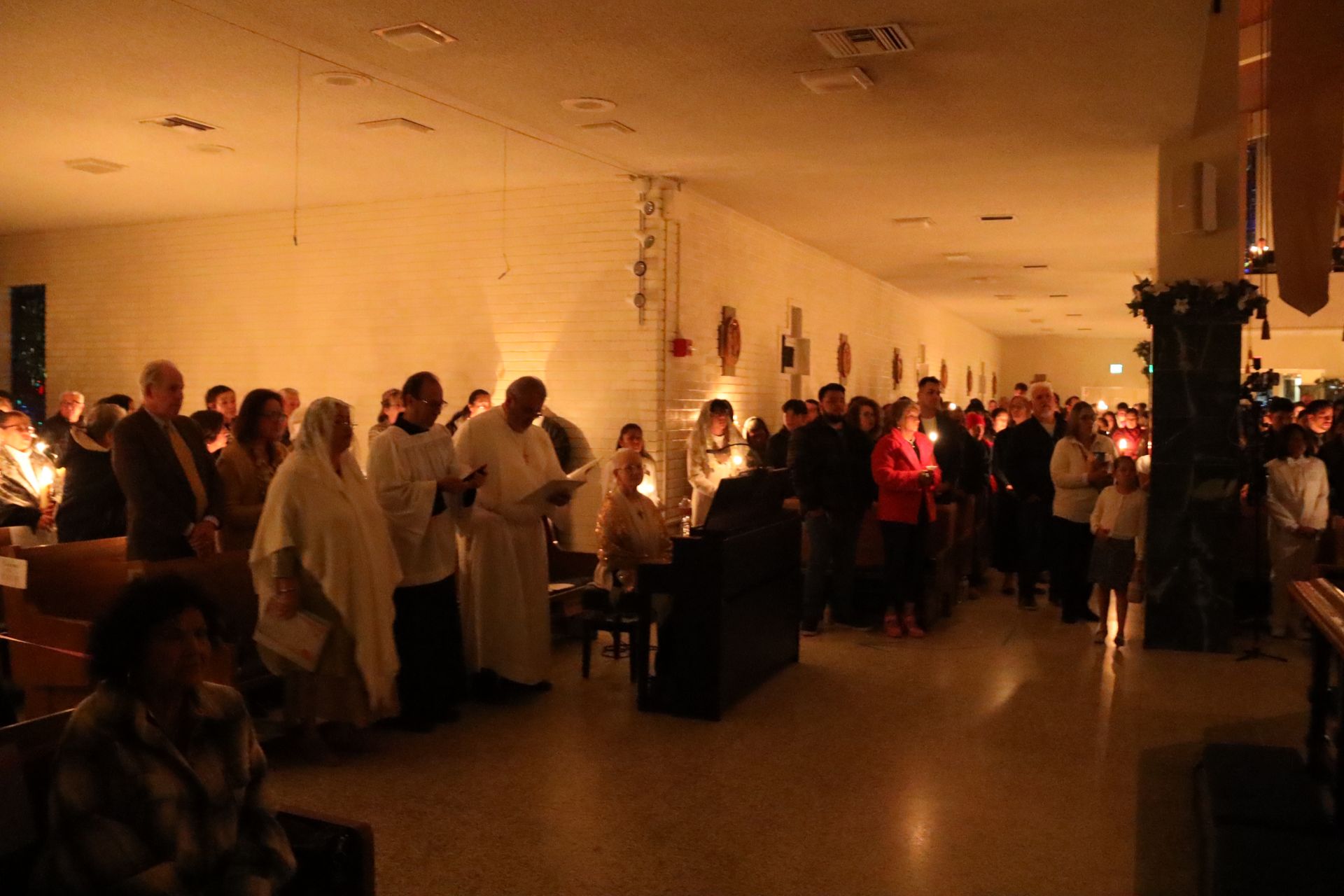Crowded banquet hall with people mingling around long tables under warm lighting