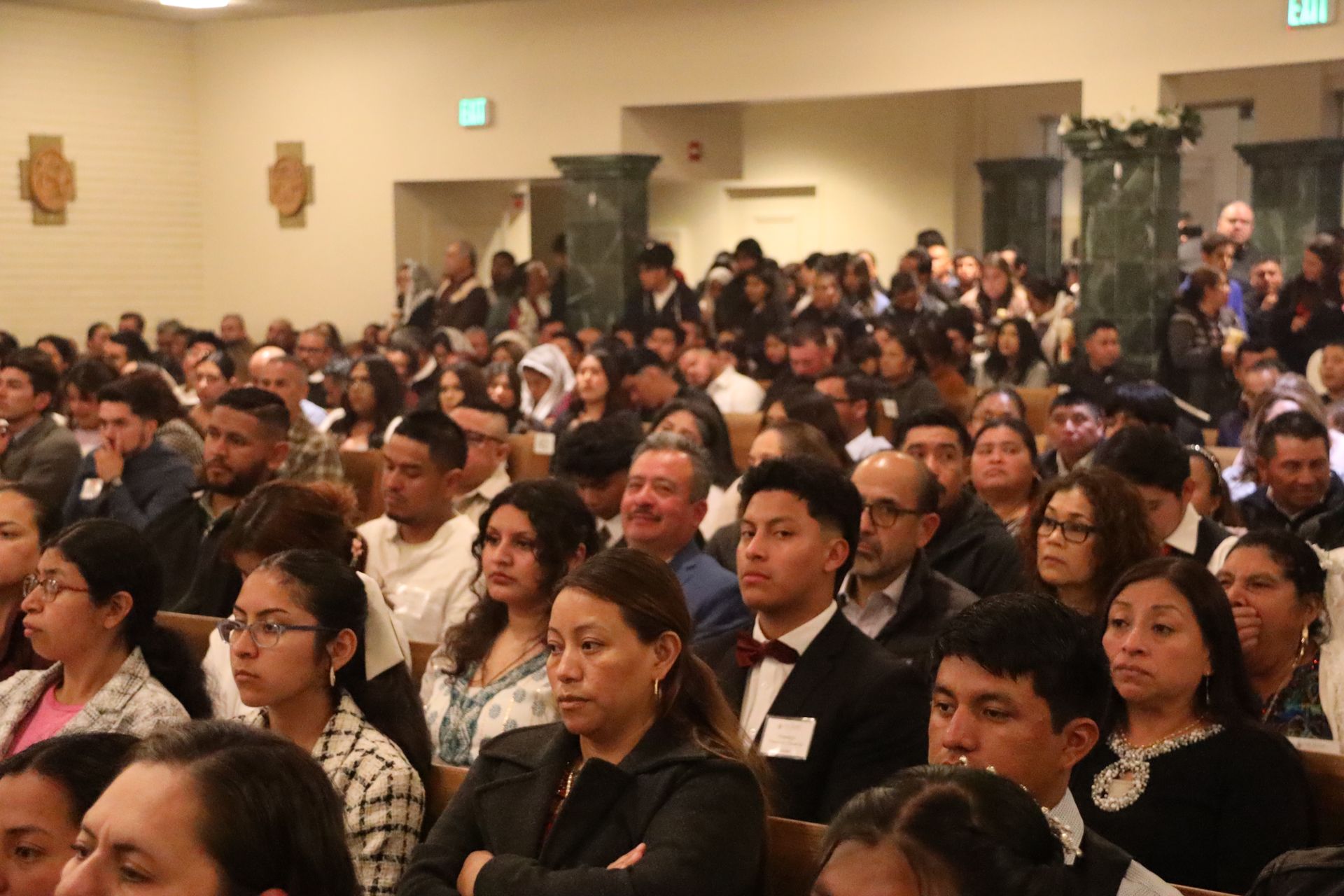 Audience seated at a conference, listening attentively in a large indoor hall