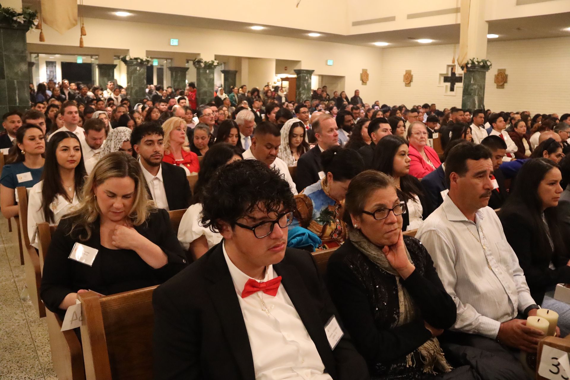 Audience seated in a hall, listening during a formal event.