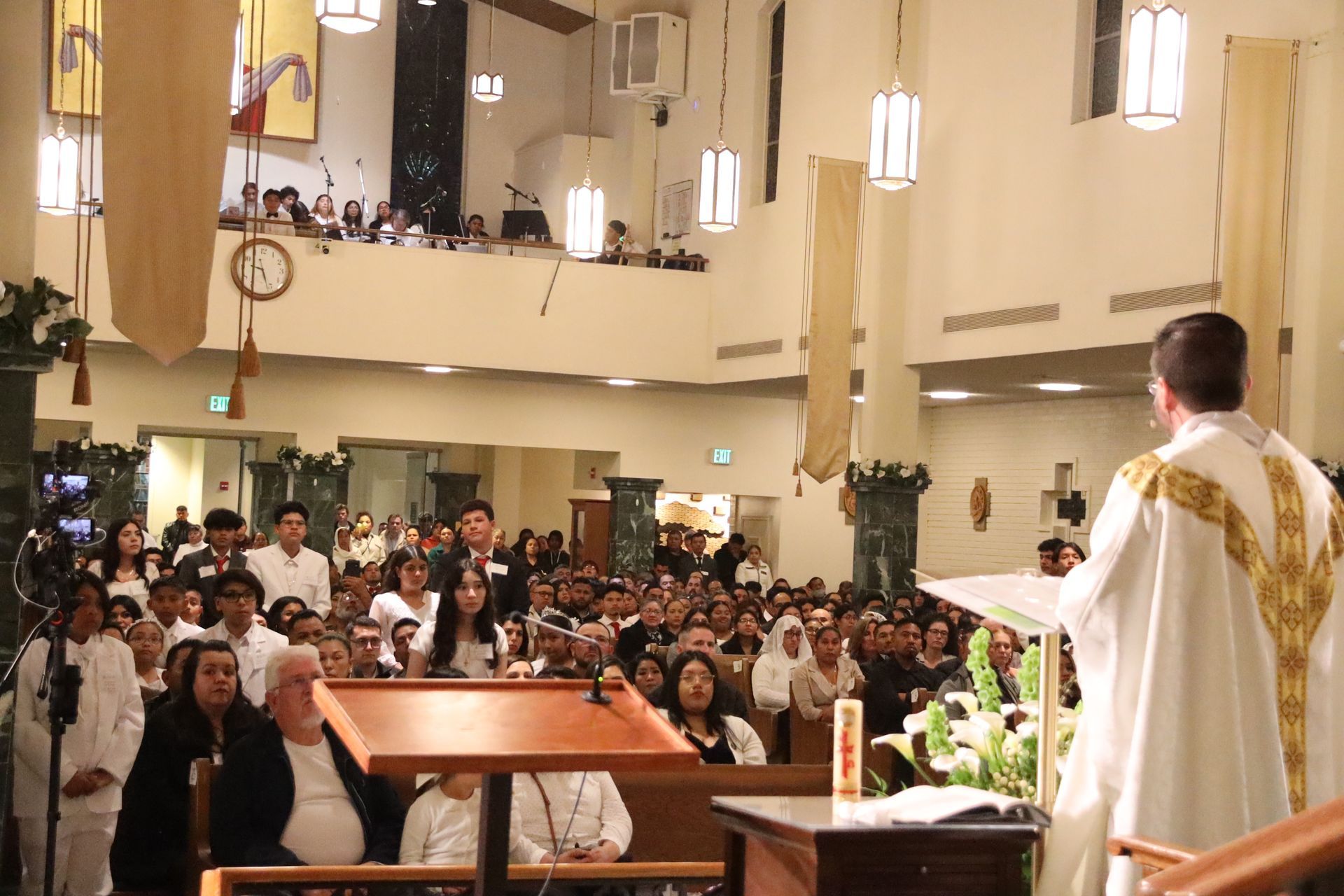 Priest speaking at the altar to a crowded church congregation during a service