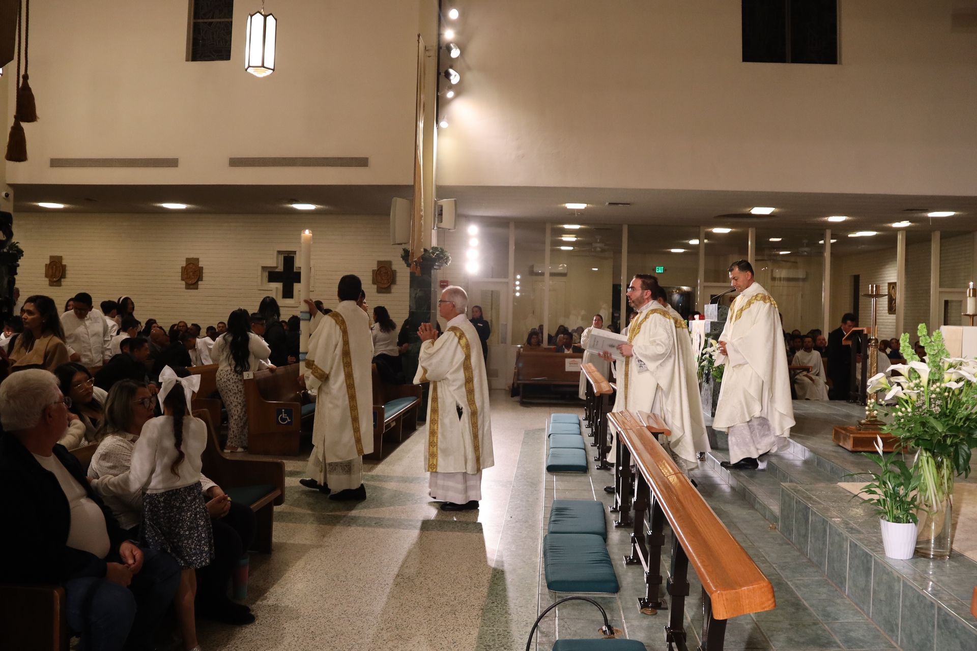 Priests in white robes process down the aisle inside a church during a ceremony