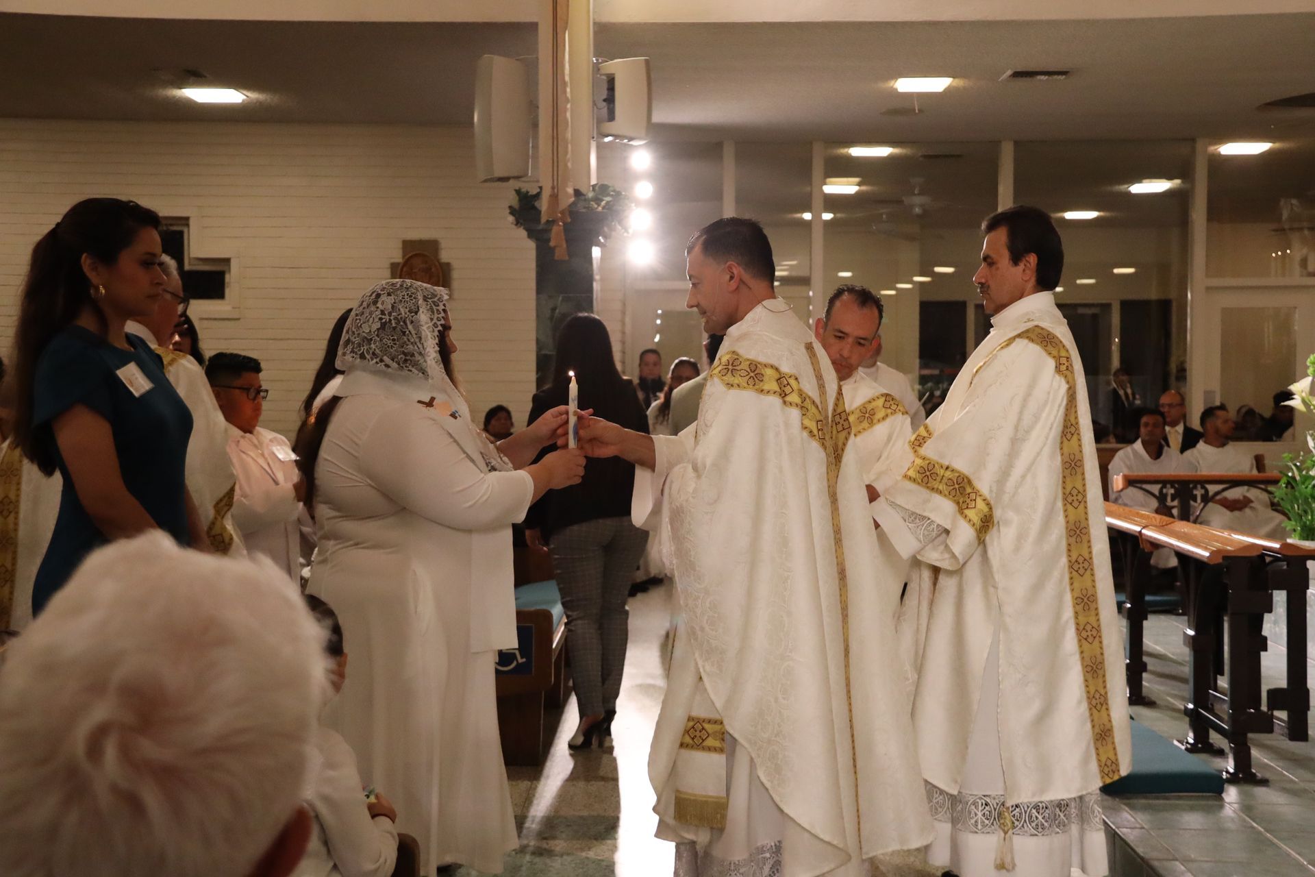 People in white ceremonial robes gathered indoors, facing each other during a religious service