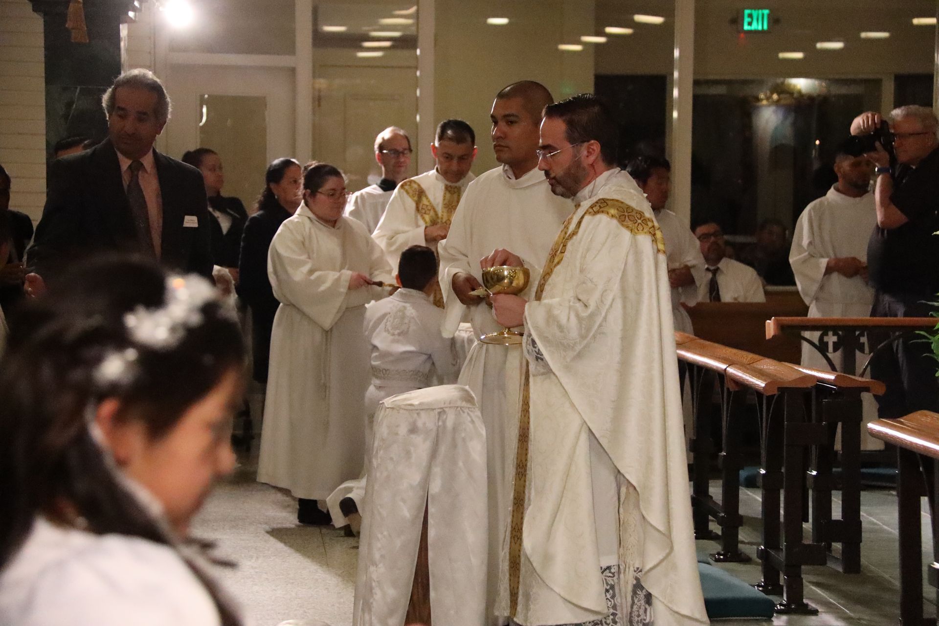 Priest in white vestments blessing a couple in a church during a wedding ceremony