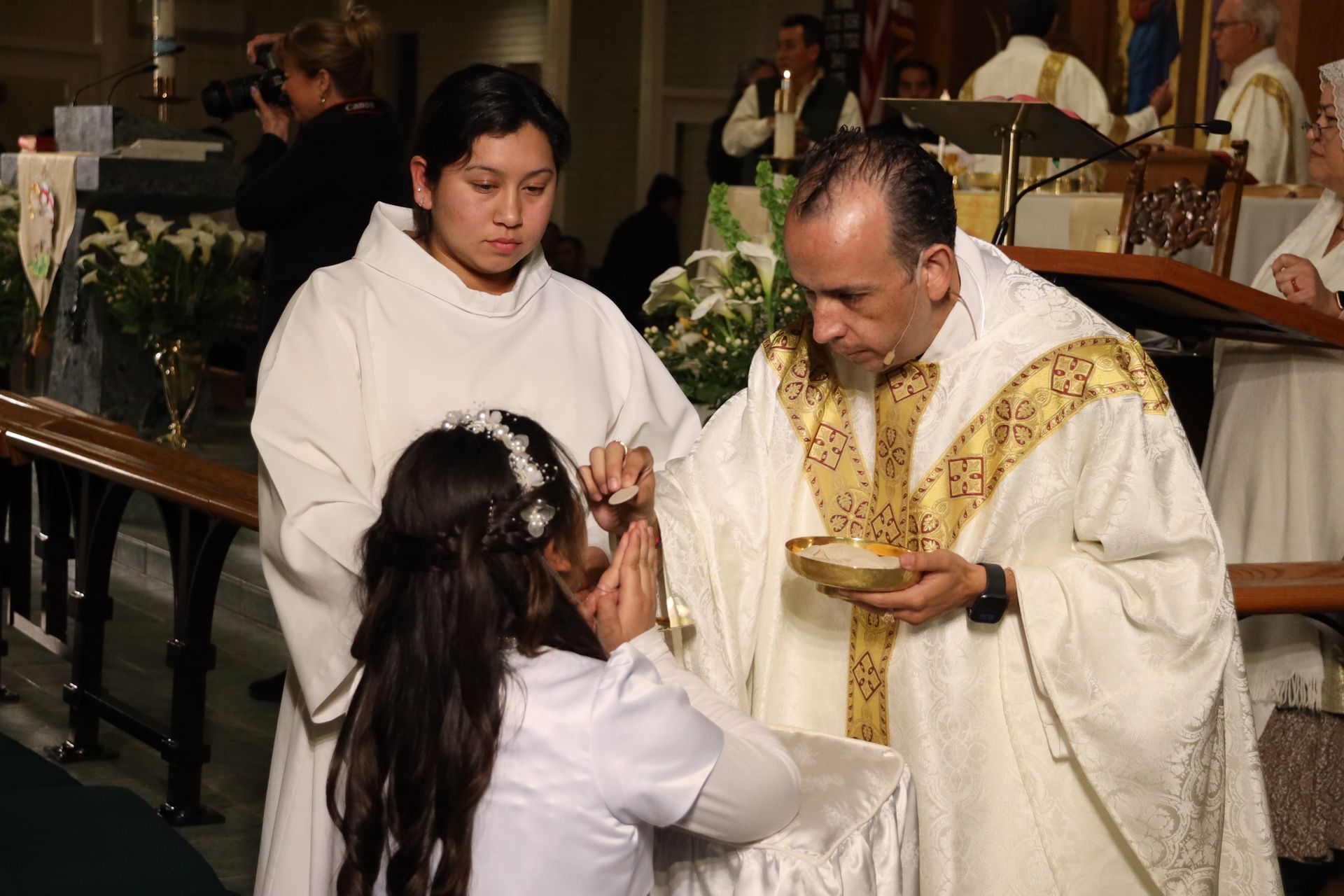 Priest giving communion to a kneeling person in a church ceremony
