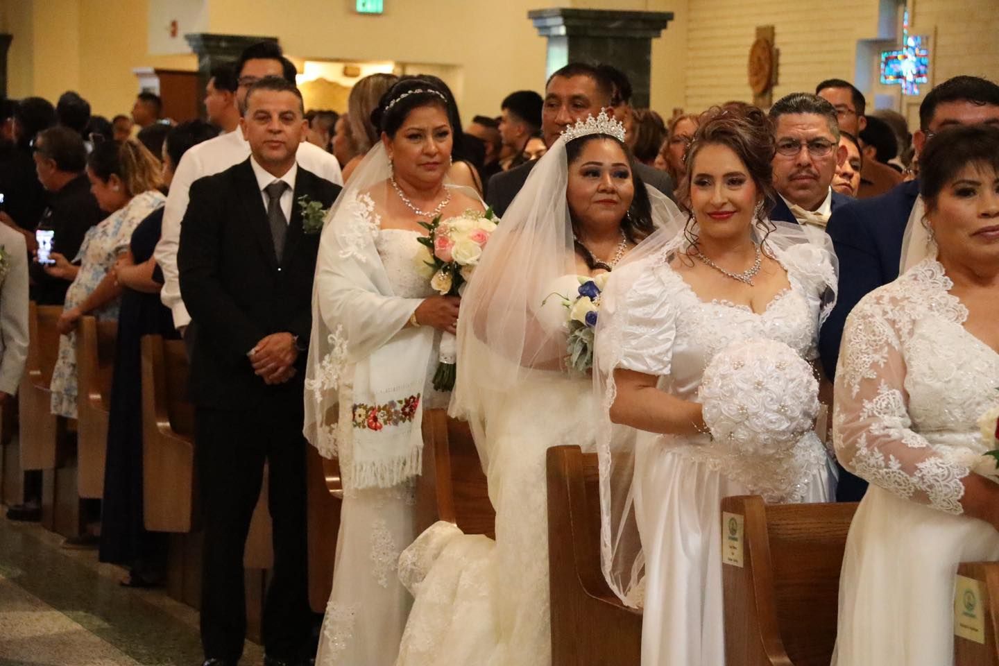 Bride and wedding party seated in a church aisle during a ceremony
